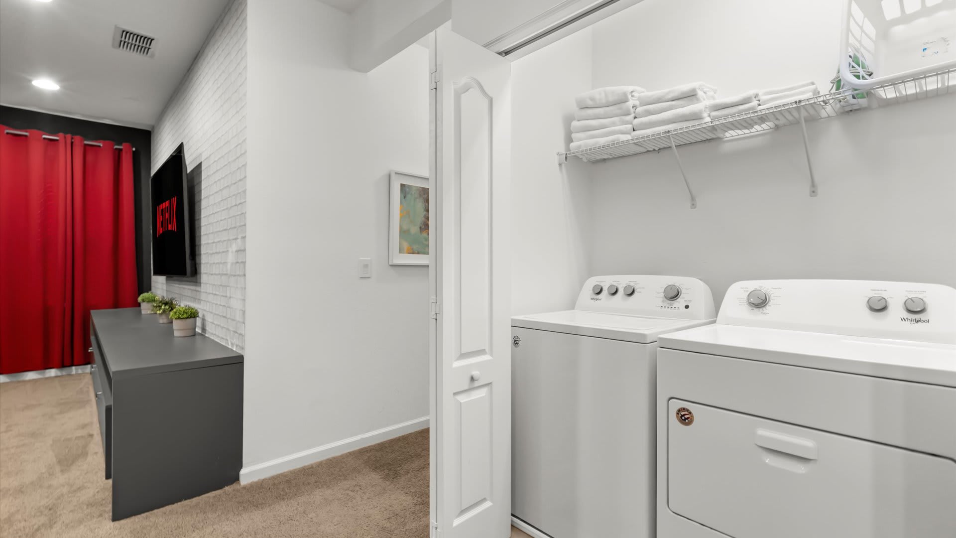 Laundry room with washer, dryer, and ample shelving.