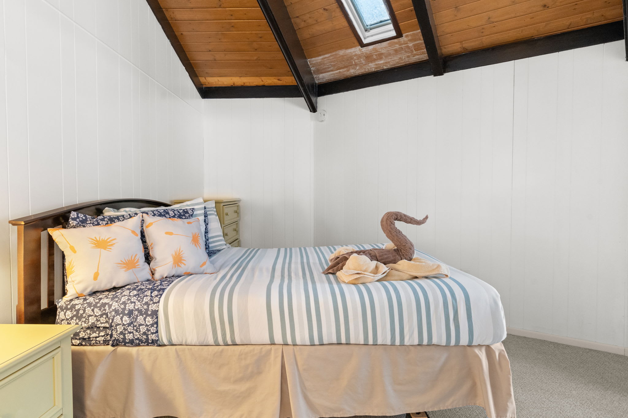 Welcoming queen bedroom with elegant swan decor and striped linens in Pocono cabin
