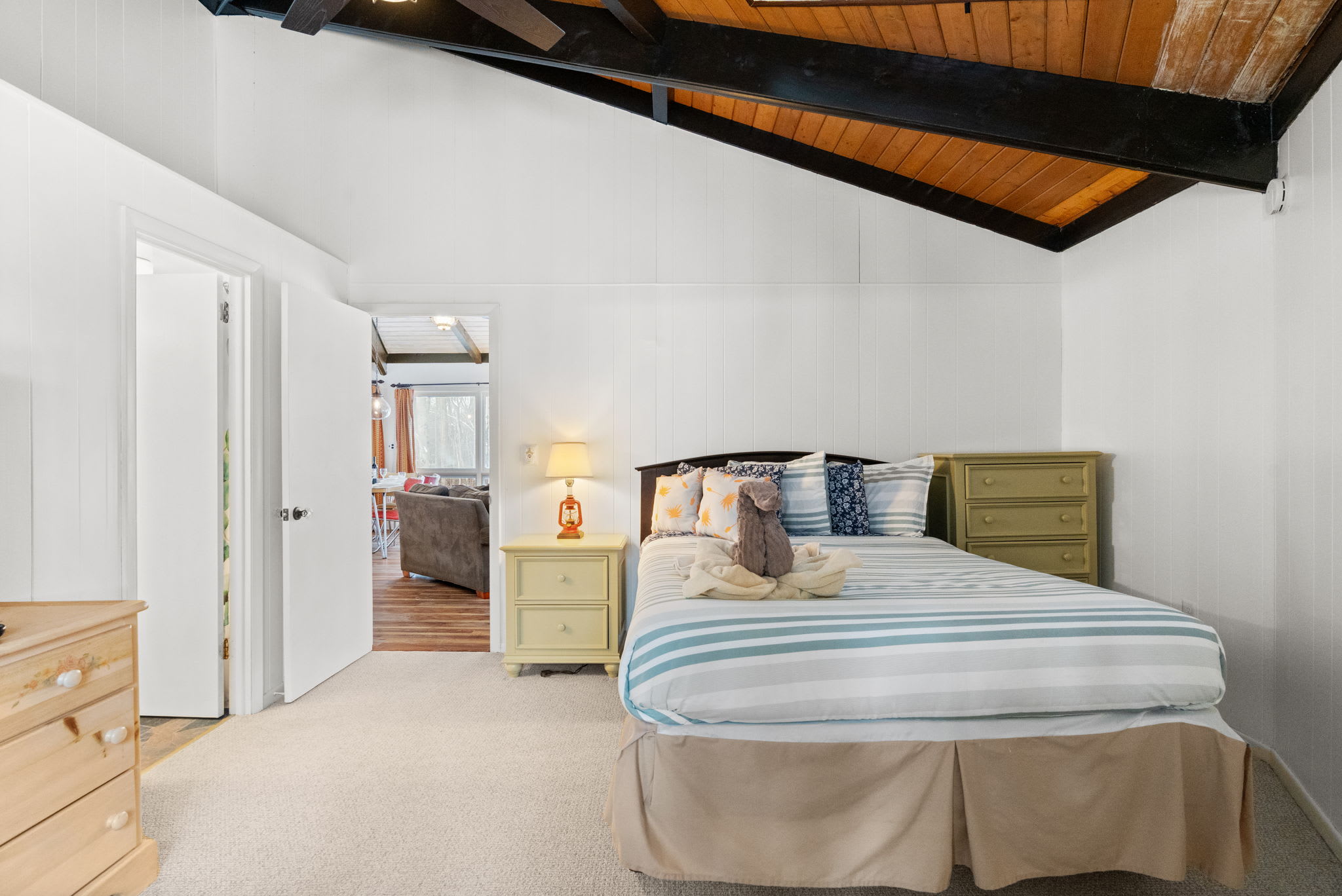 Bright queen bedroom with coastal-striped bedding under vaulted A-frame ceiling in Lake Naomi cabin