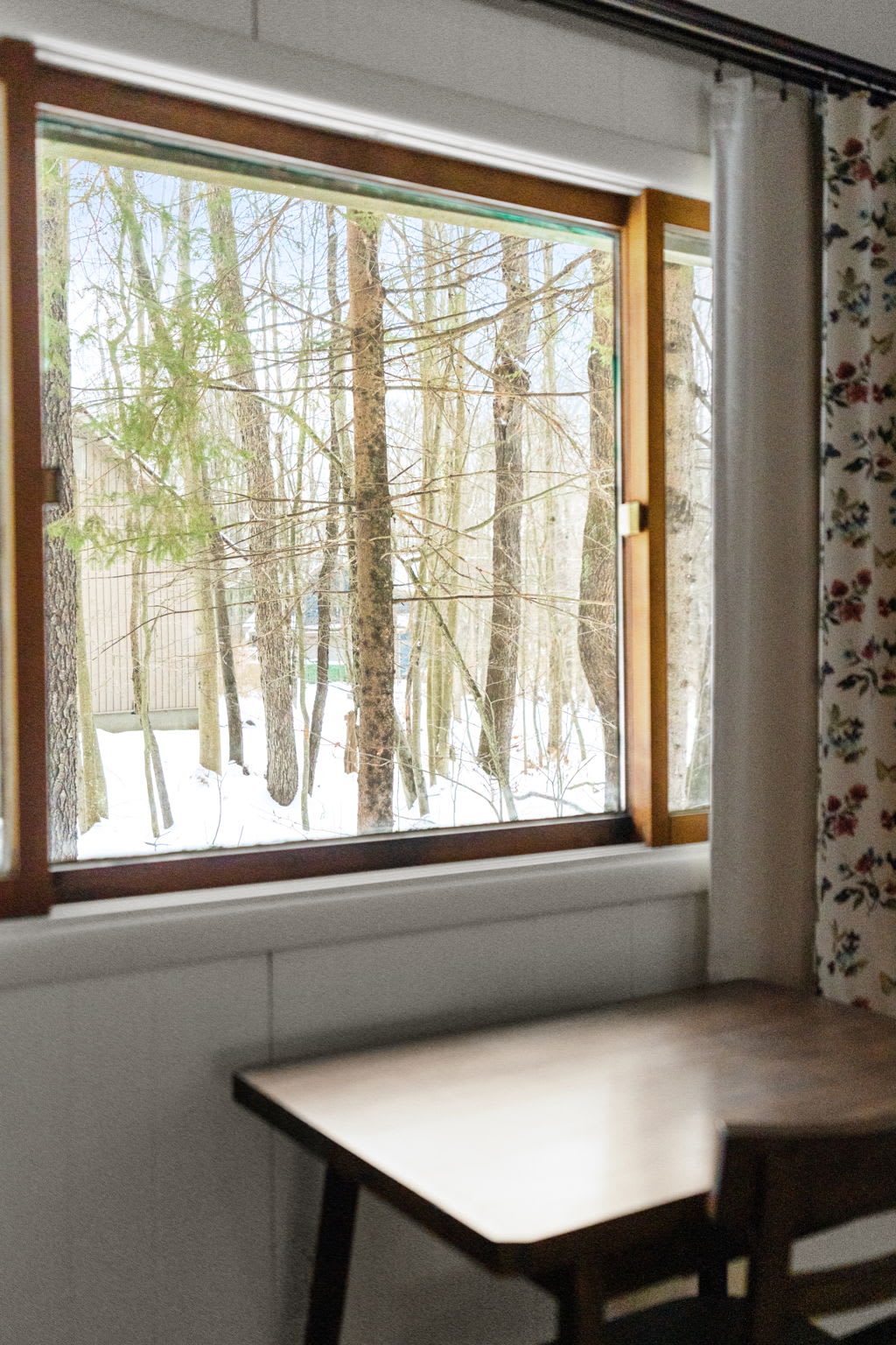 Serene bedroom with forest window views and comfy seating at Lake Naomi Pocono retreat