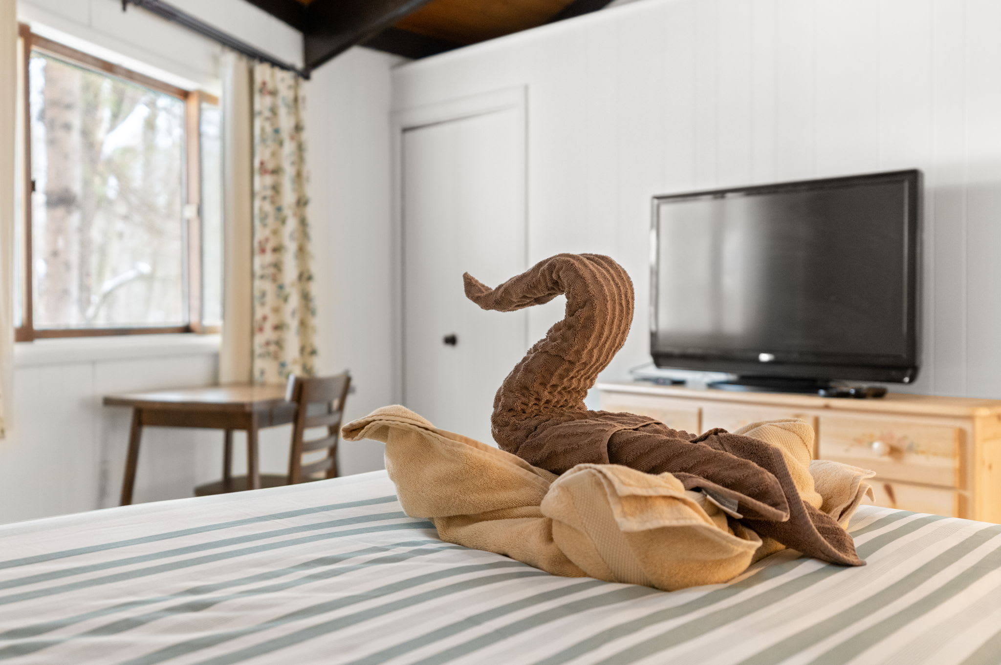 Charming queen bedroom featuring decorative swan art and natural light in Lake Naomi retreat