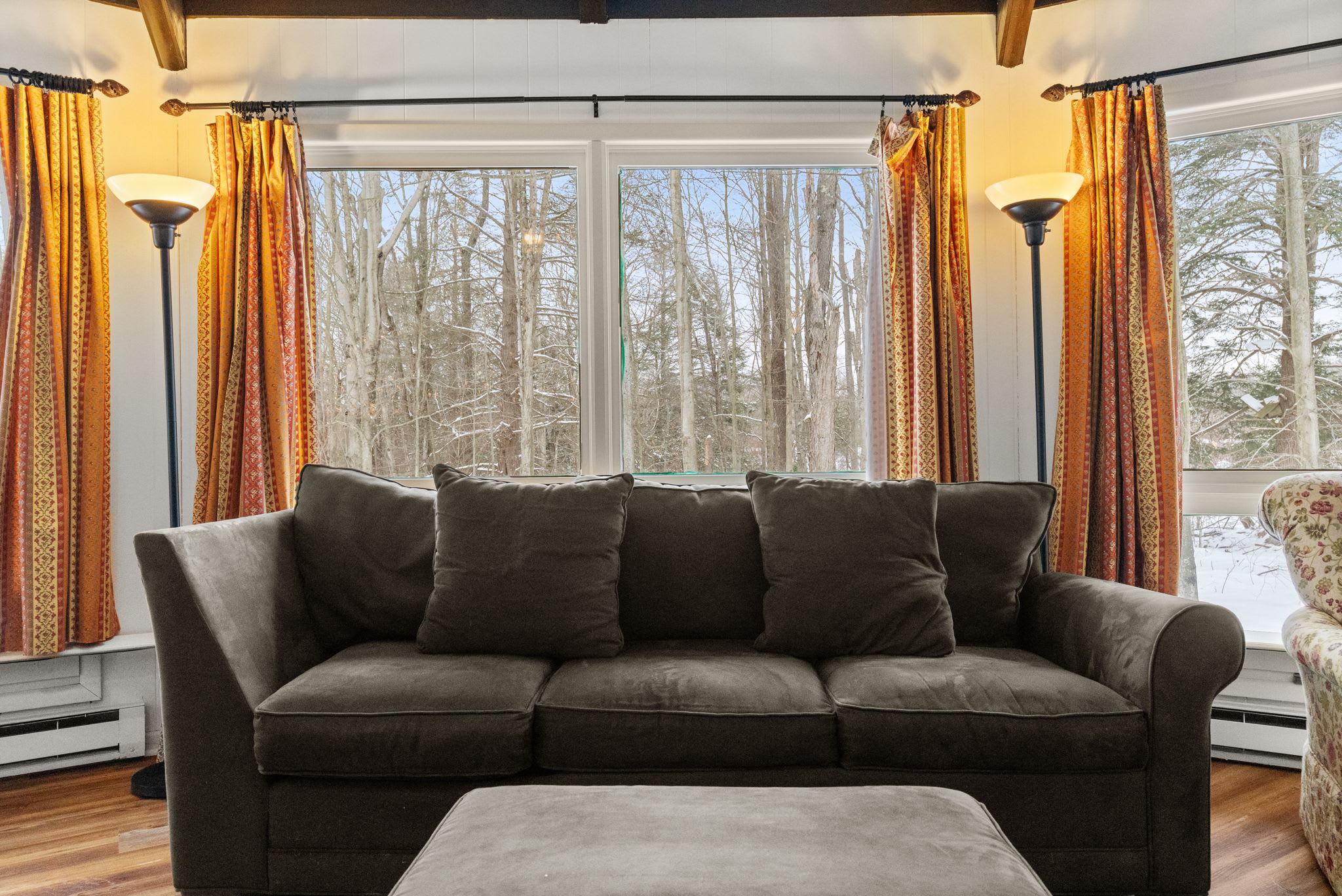Scenic living room with plush sofa and panoramic forest views at Pocono Mountains retreat