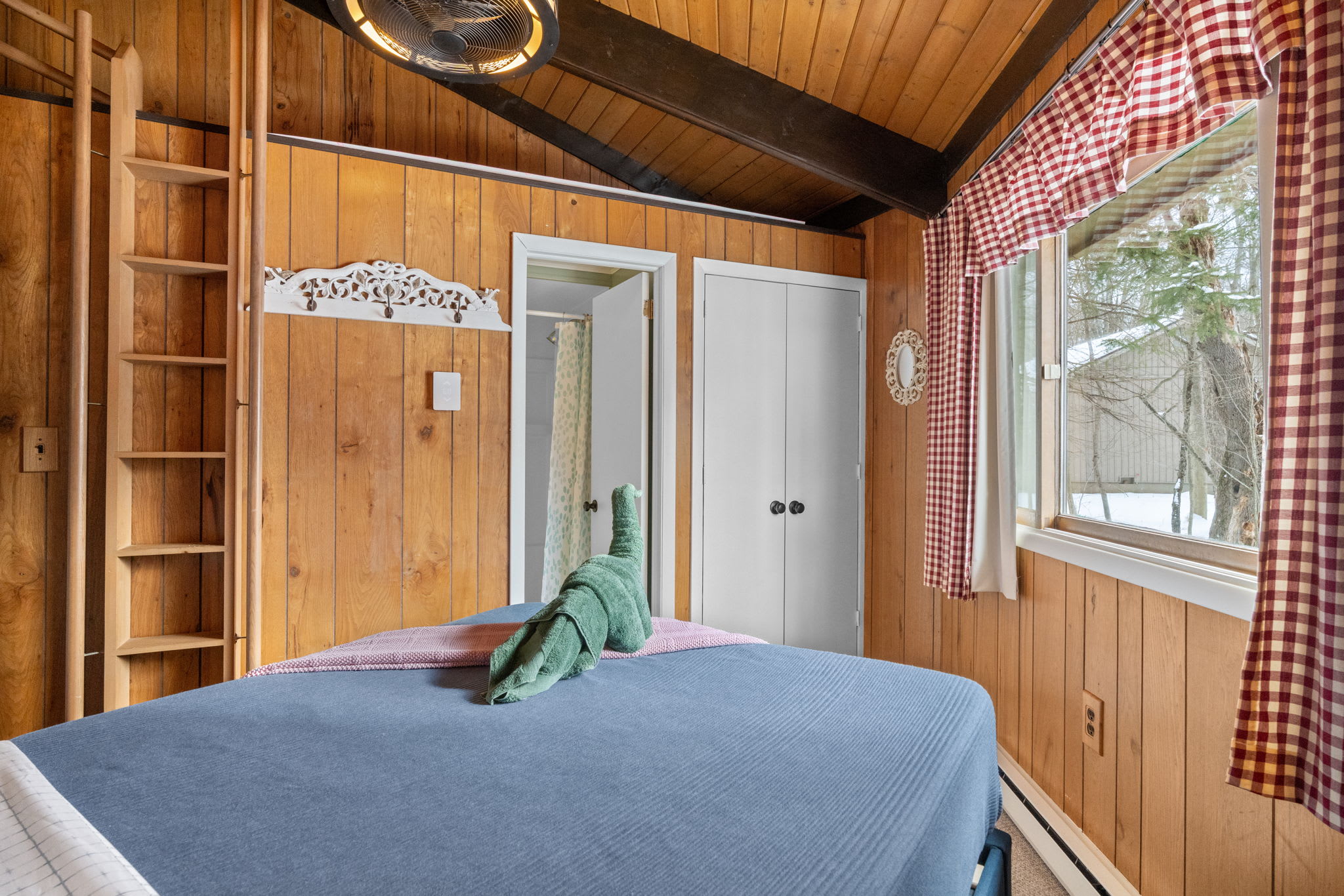 Charming bedroom with red accent wall and rustic wood paneling in Lake Naomi Pocono cabin