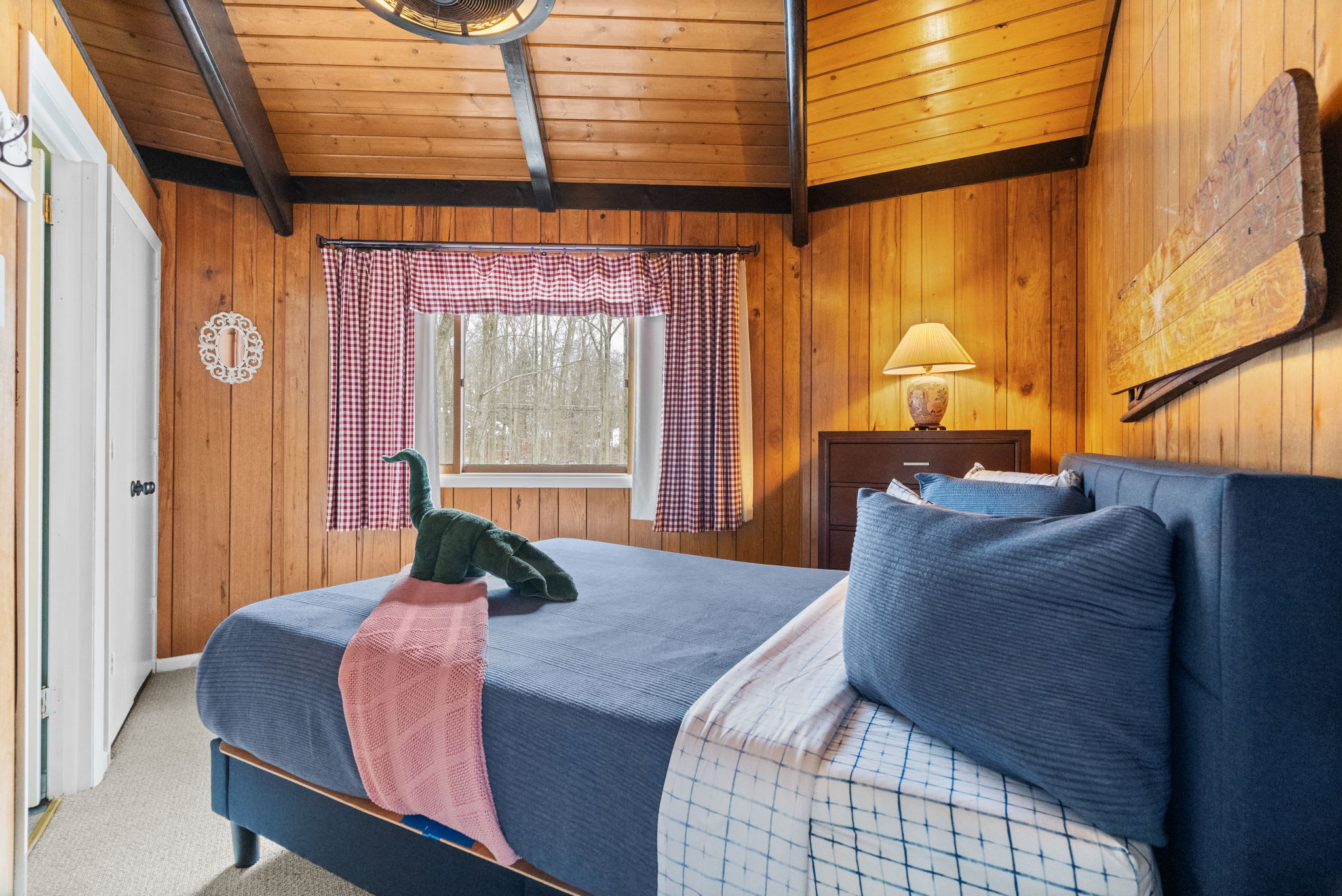 Cozy bedroom with blue bedding and rustic wood walls in Lake Naomi cabin