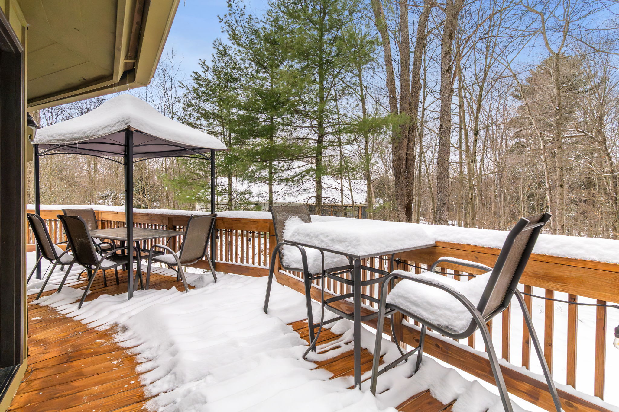Peaceful snow-covered deck overlooking winter woodland at Lake Naomi Pocono cabin retreat