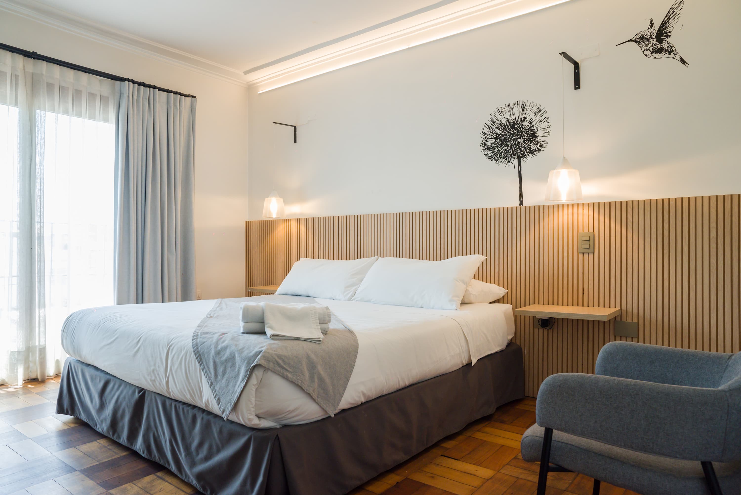 Relax in this stylish bedroom with modern decor, cozy bedding, and ample natural light, perfect for a restful stay.