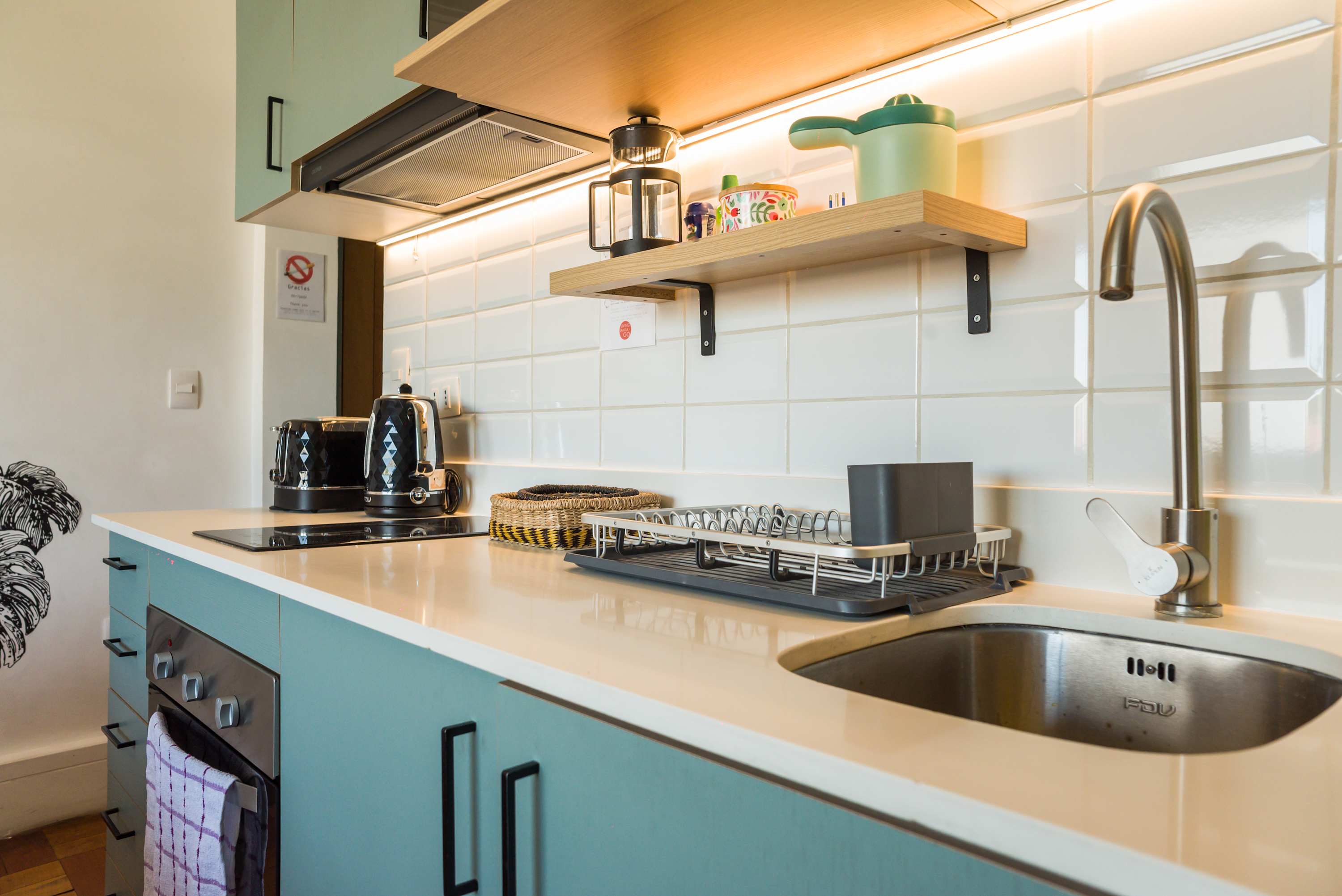 Sleek and modern kitchen with stylish teal cabinets and convenient appliances, perfect for a cozy meal preparation.