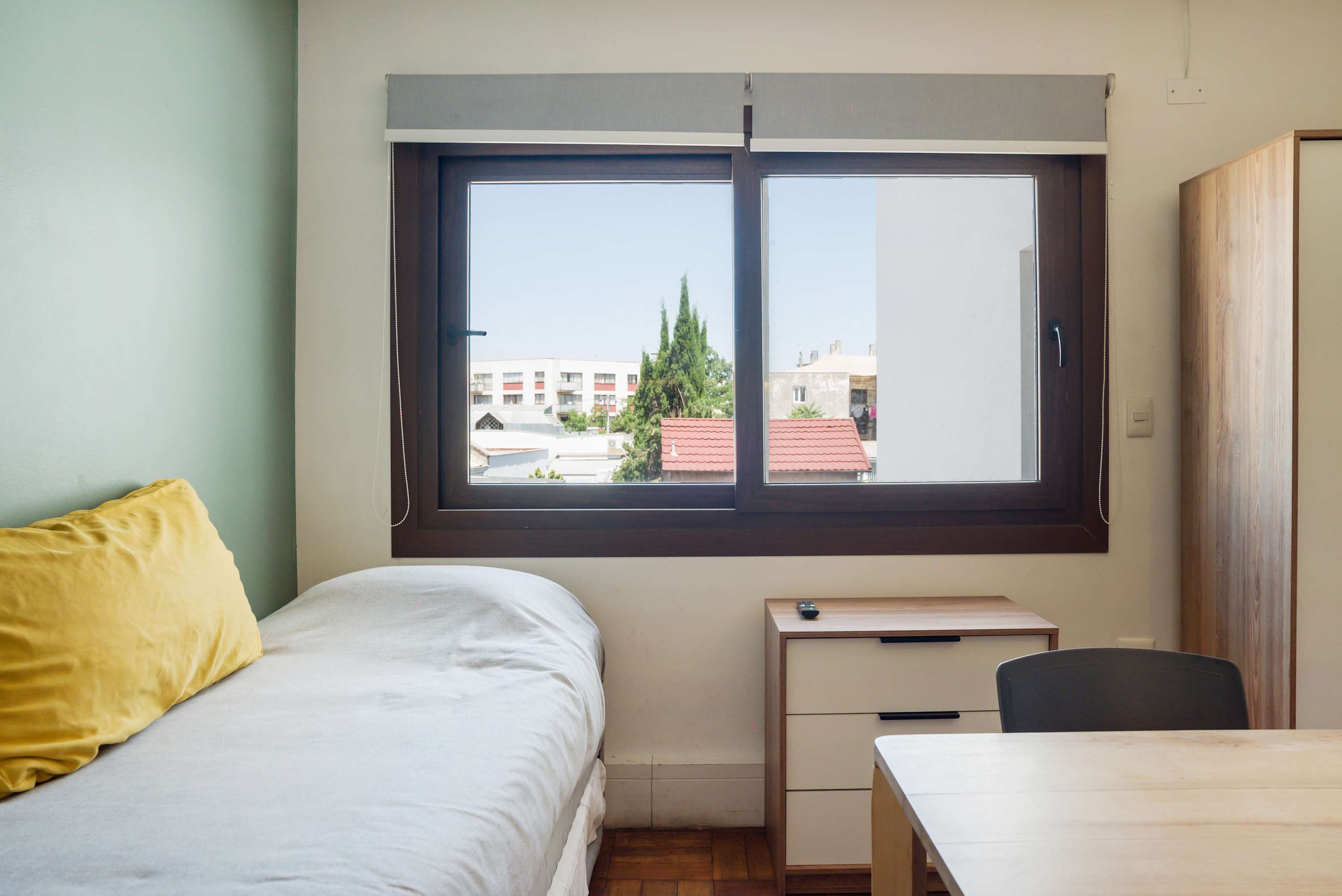 Cozy bedroom with a bright window view, perfect for relaxation and work.