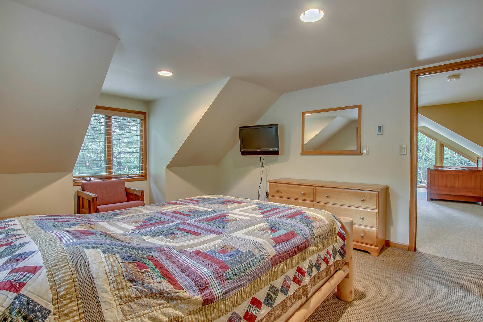 Top floor bedroom offers a peaceful escape with rustic log bed and plenty of storage
