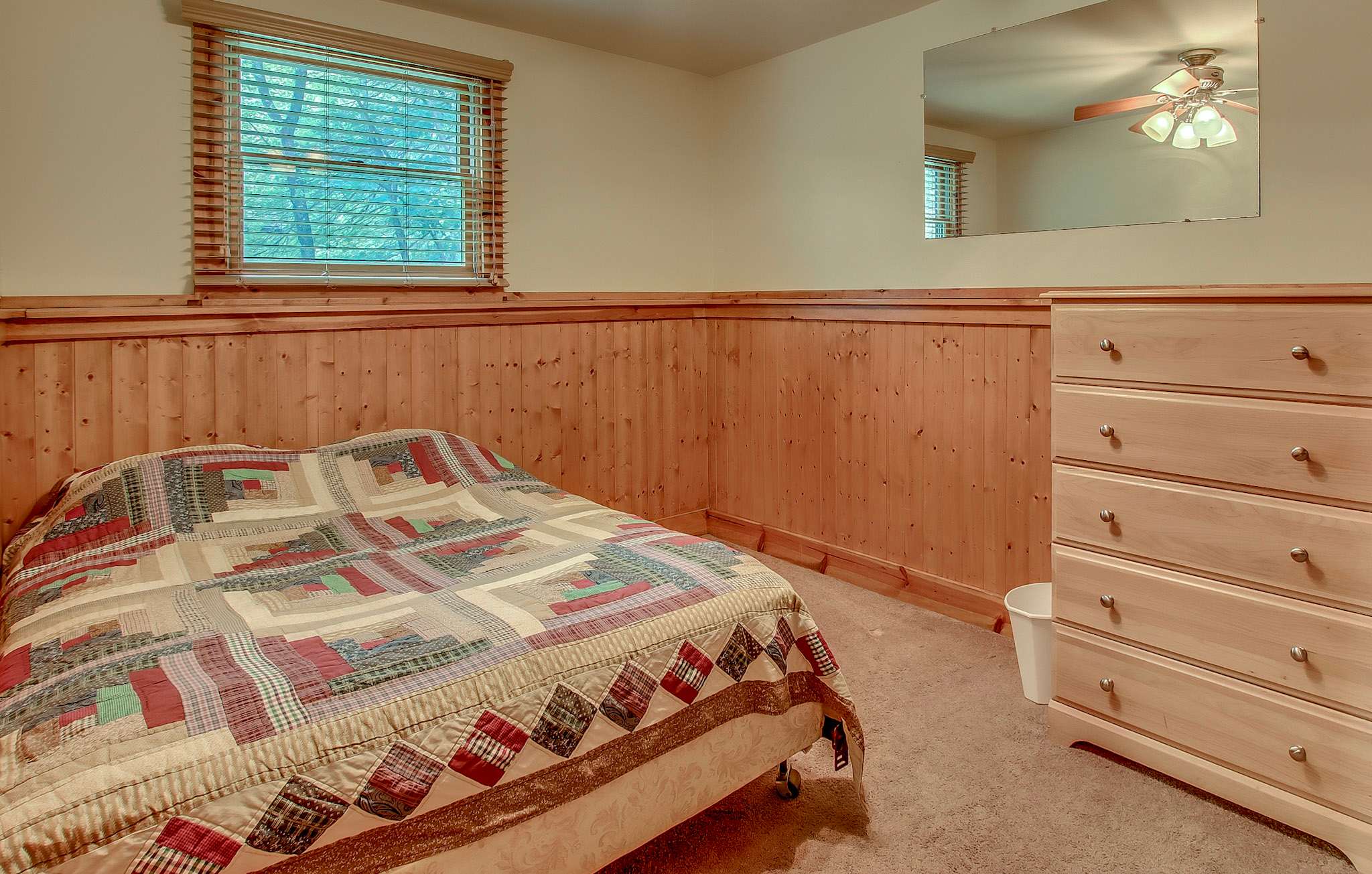 Rest easy in this cabin-style bedroom with ample dresser storage and warm wood accents