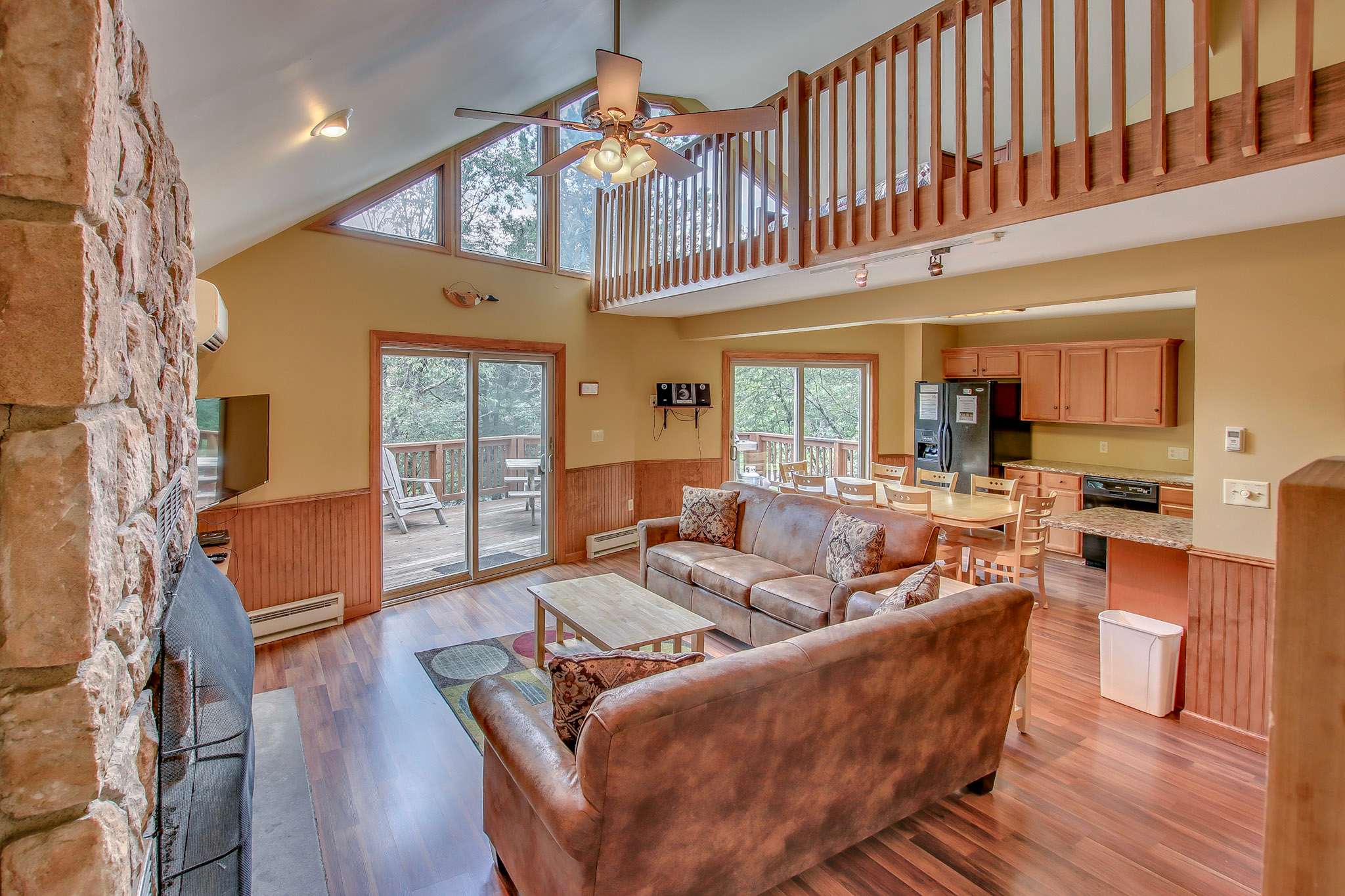 Open concept living area with soaring ceilings, loft balcony, and fireplace focal point