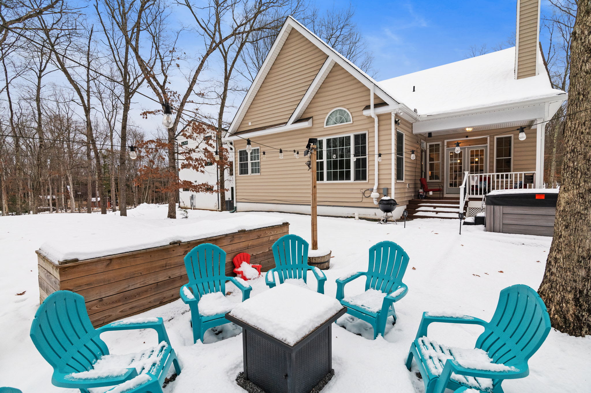 Spacious outdoor deck with Adirondack seating overlooking private wooded backyard - perfect for morning coffee
