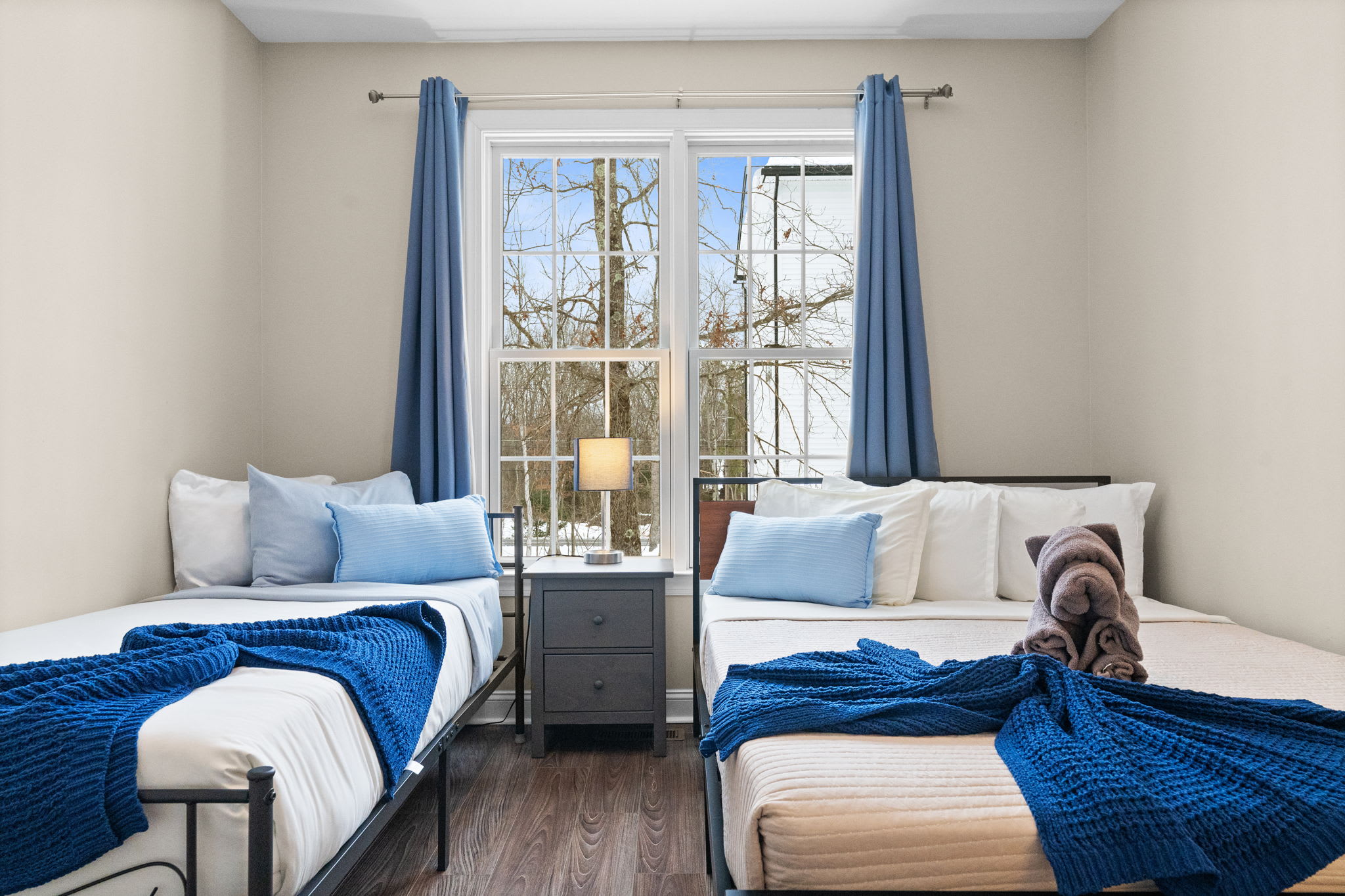 Beautifully appointed second bedroom featuring queen bed with plush blue bedding and forest views