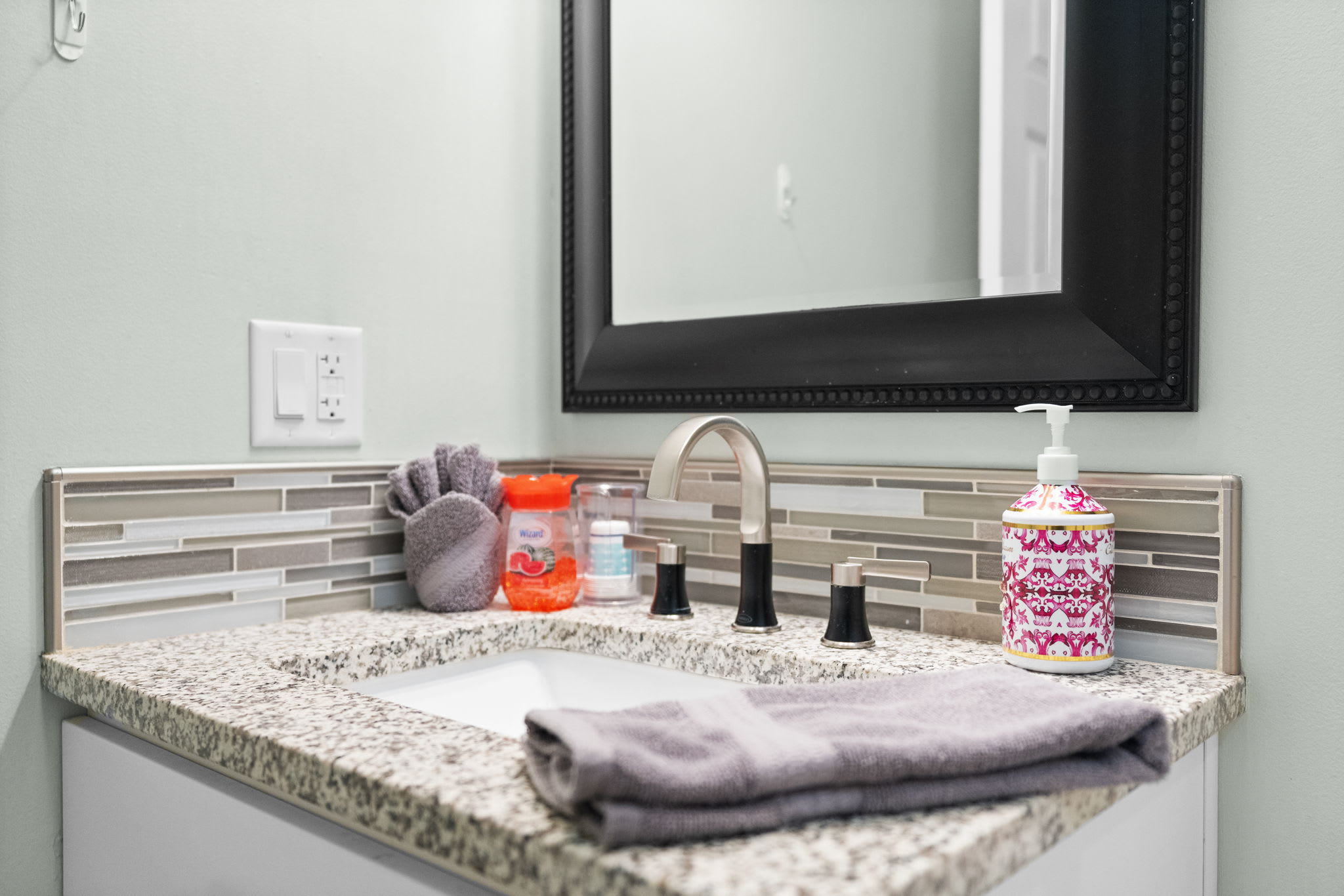Well-appointed bathroom with granite vanity top, quality fixtures and ample storage space