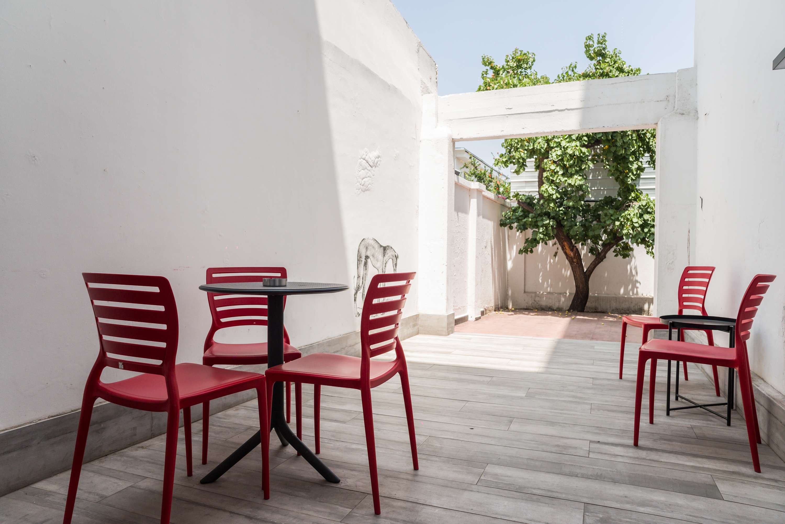 Enjoy a sunny day on this bright patio with modern seating and a refreshing view of greenery.