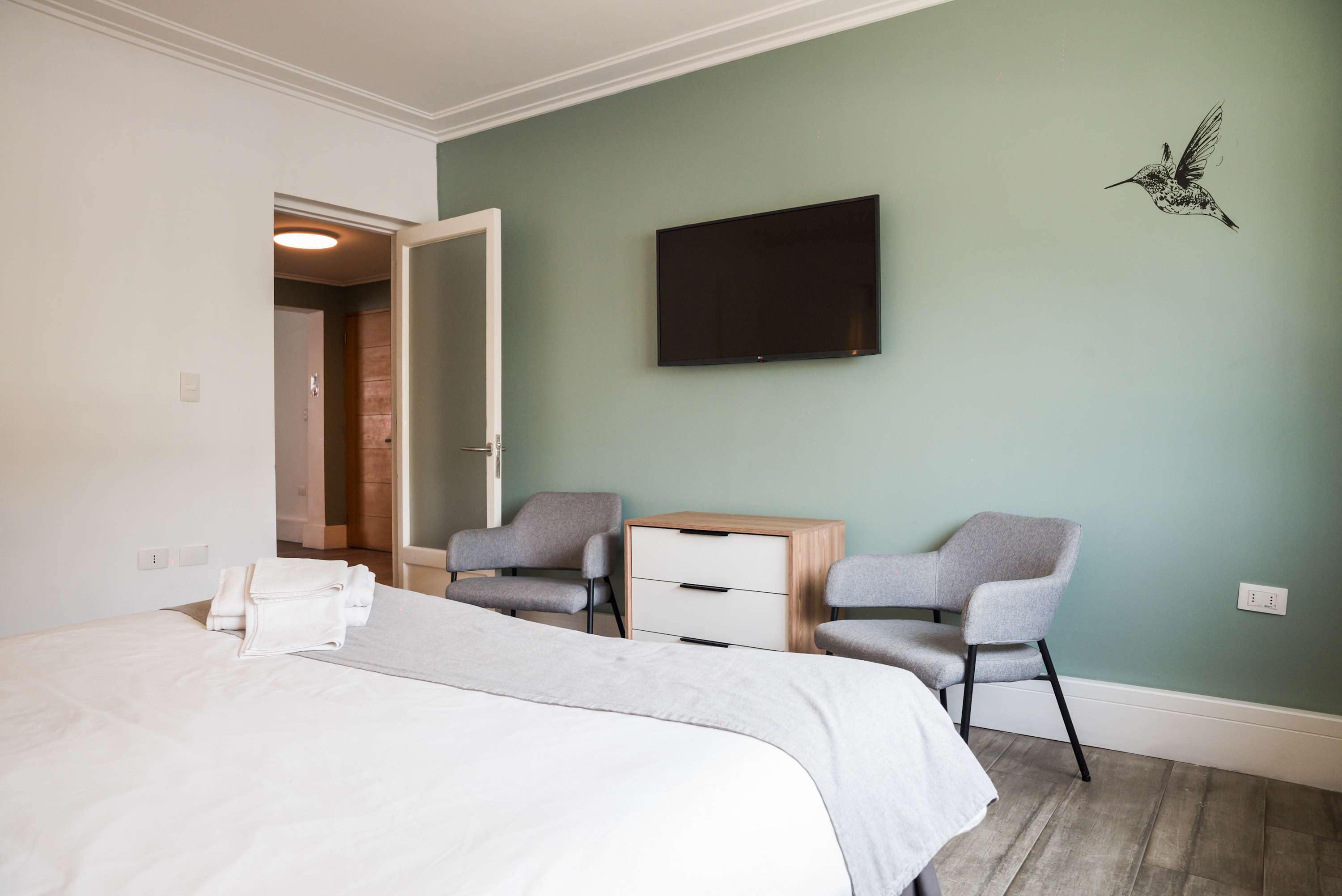 Relax in this cozy bedroom with modern decor, featuring a comfy bed, stylish seating, and a flat-screen TV for your entertainment.