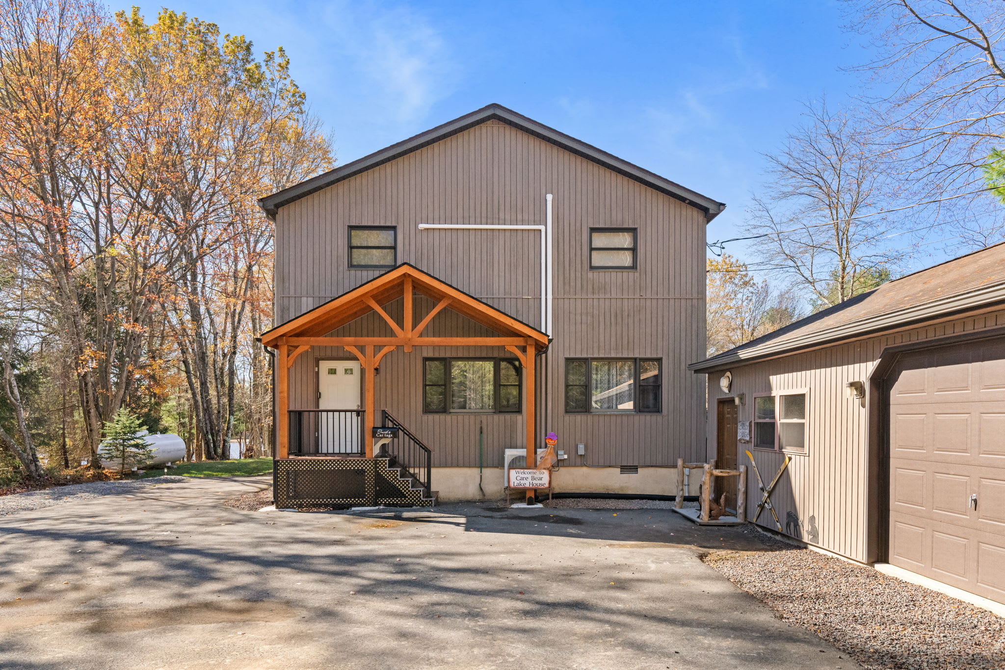 Side view showcasing garage entry and home access - well-maintained exterior with forest privacy