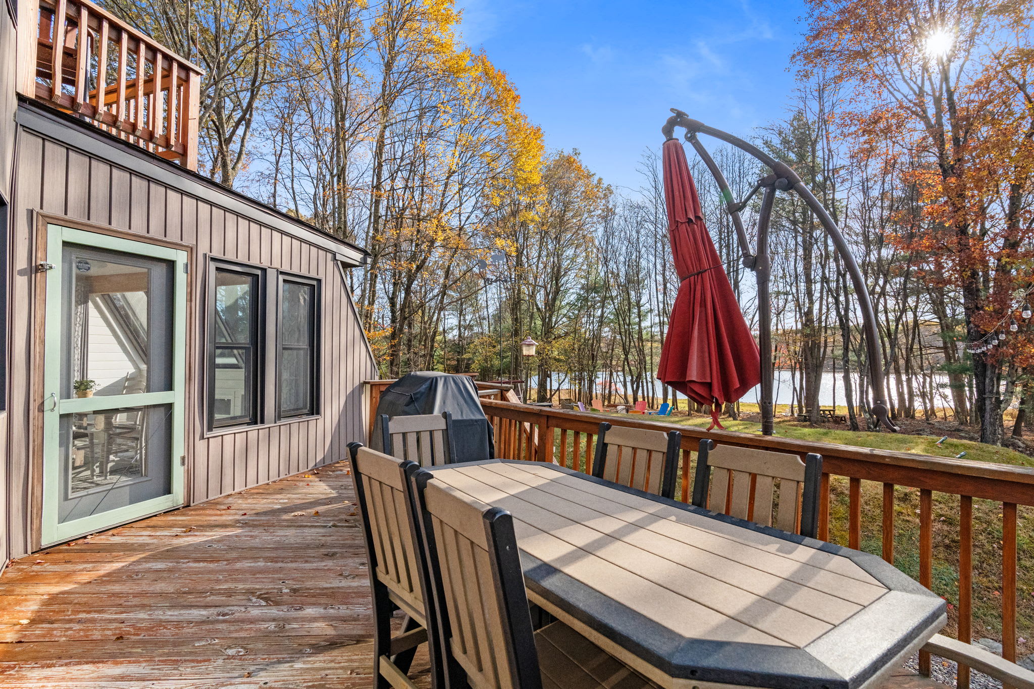 Multi-level outdoor deck with comfortable seating, gas grill, and panoramic forest views - perfect for al fresco dining