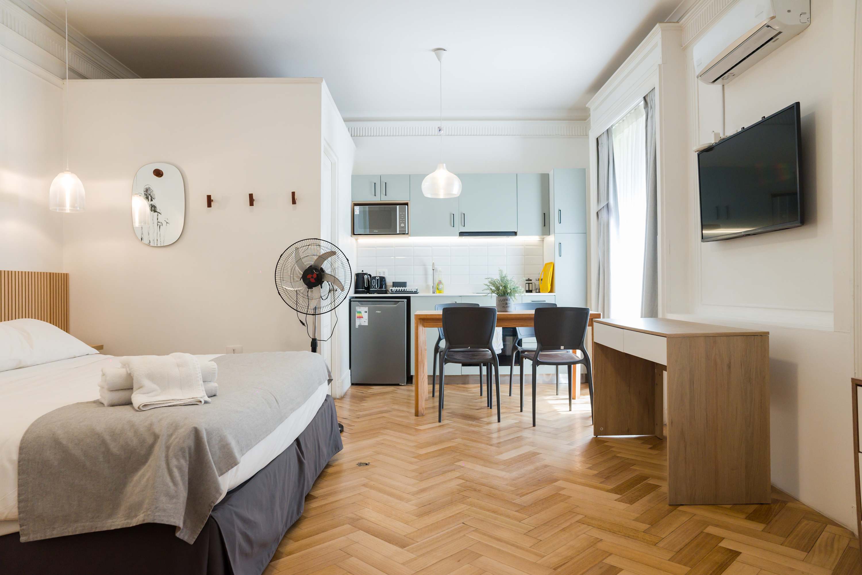 Bright and modern studio with a cozy bed, functional kitchen, and dining area perfect for a comfortable stay.