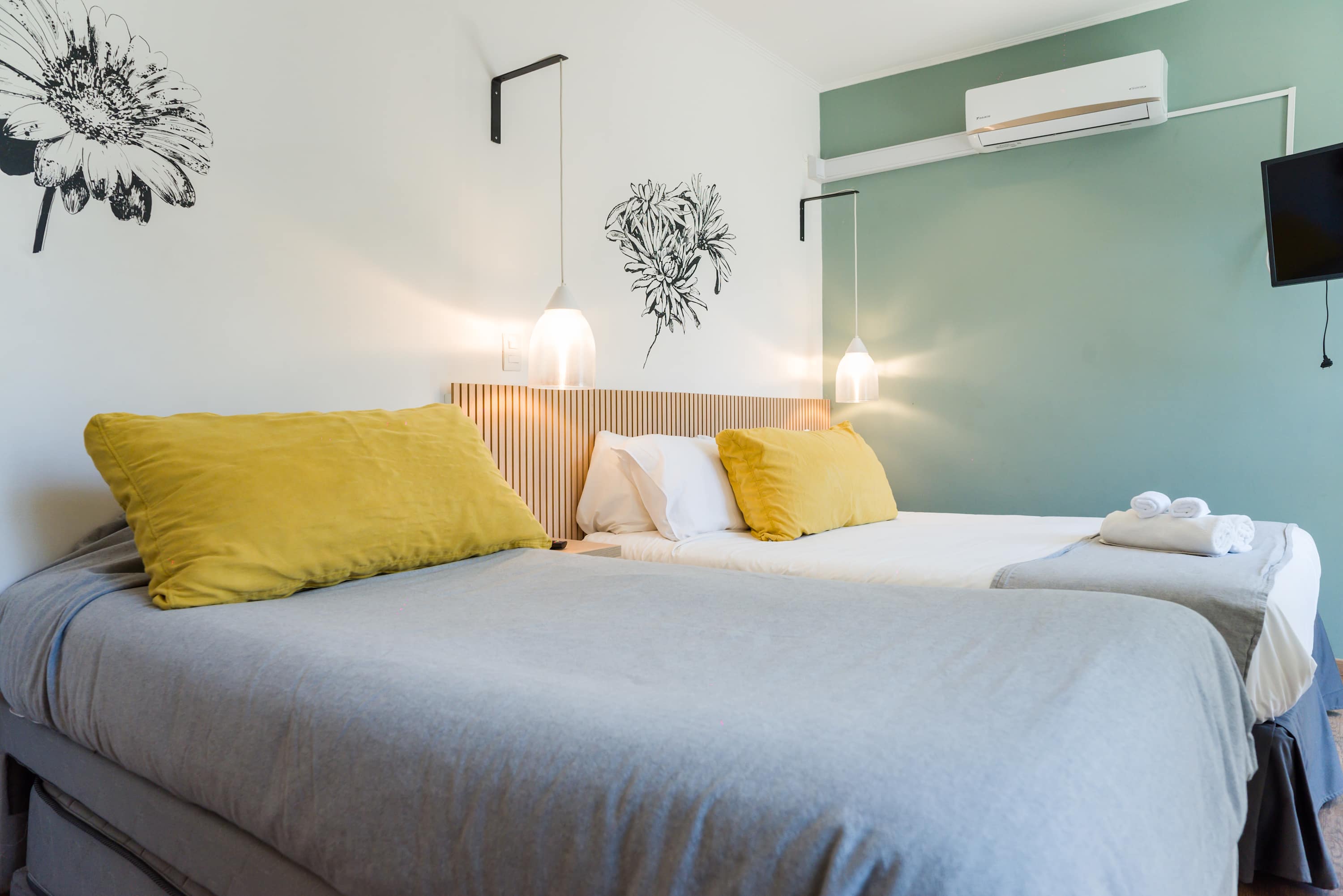 Relax in this stylish bedroom with cozy bedding, floral accents, and modern amenities for a comfortable stay.