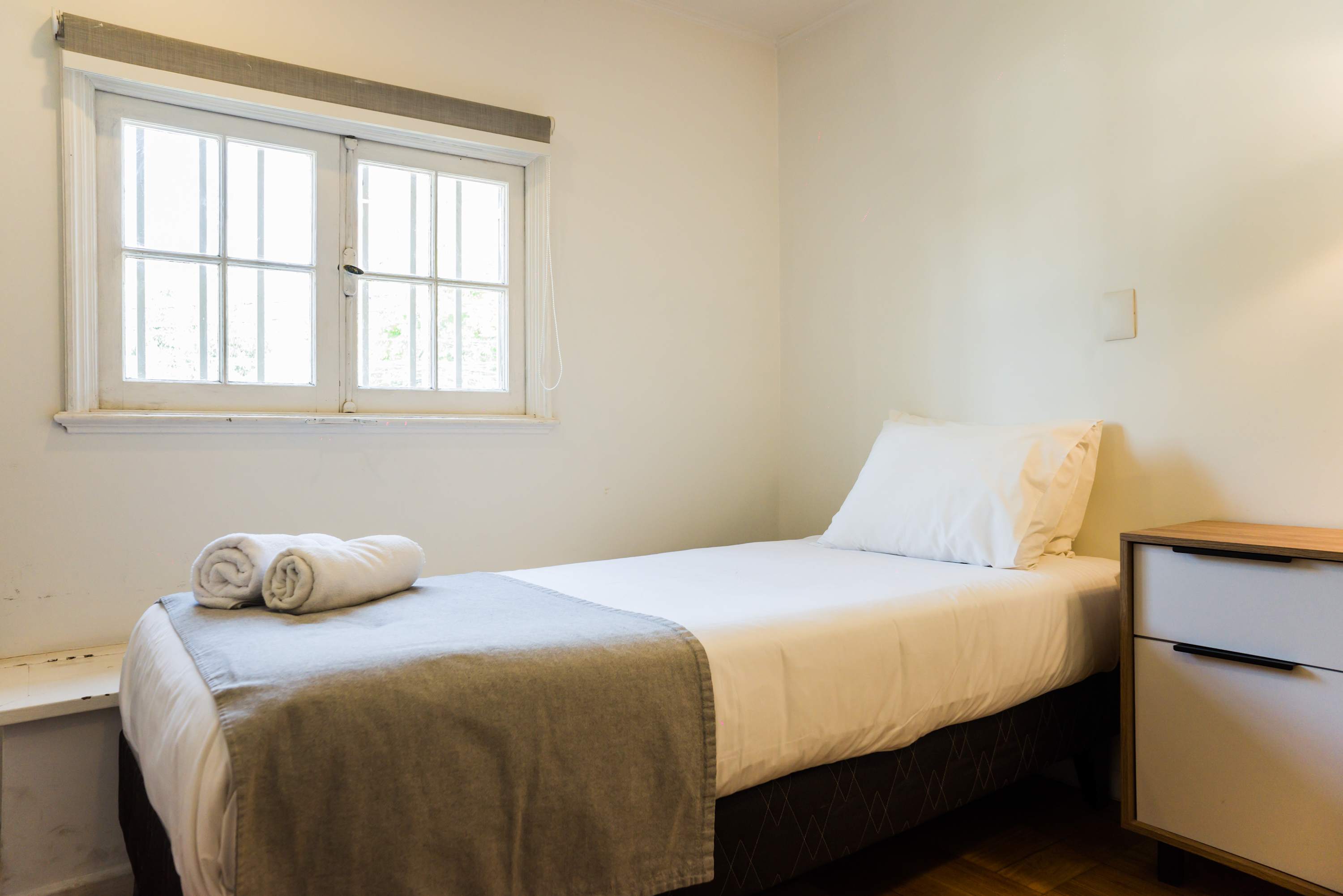 Cozy bedroom with natural light and comfortable bedding, perfect for a restful stay.