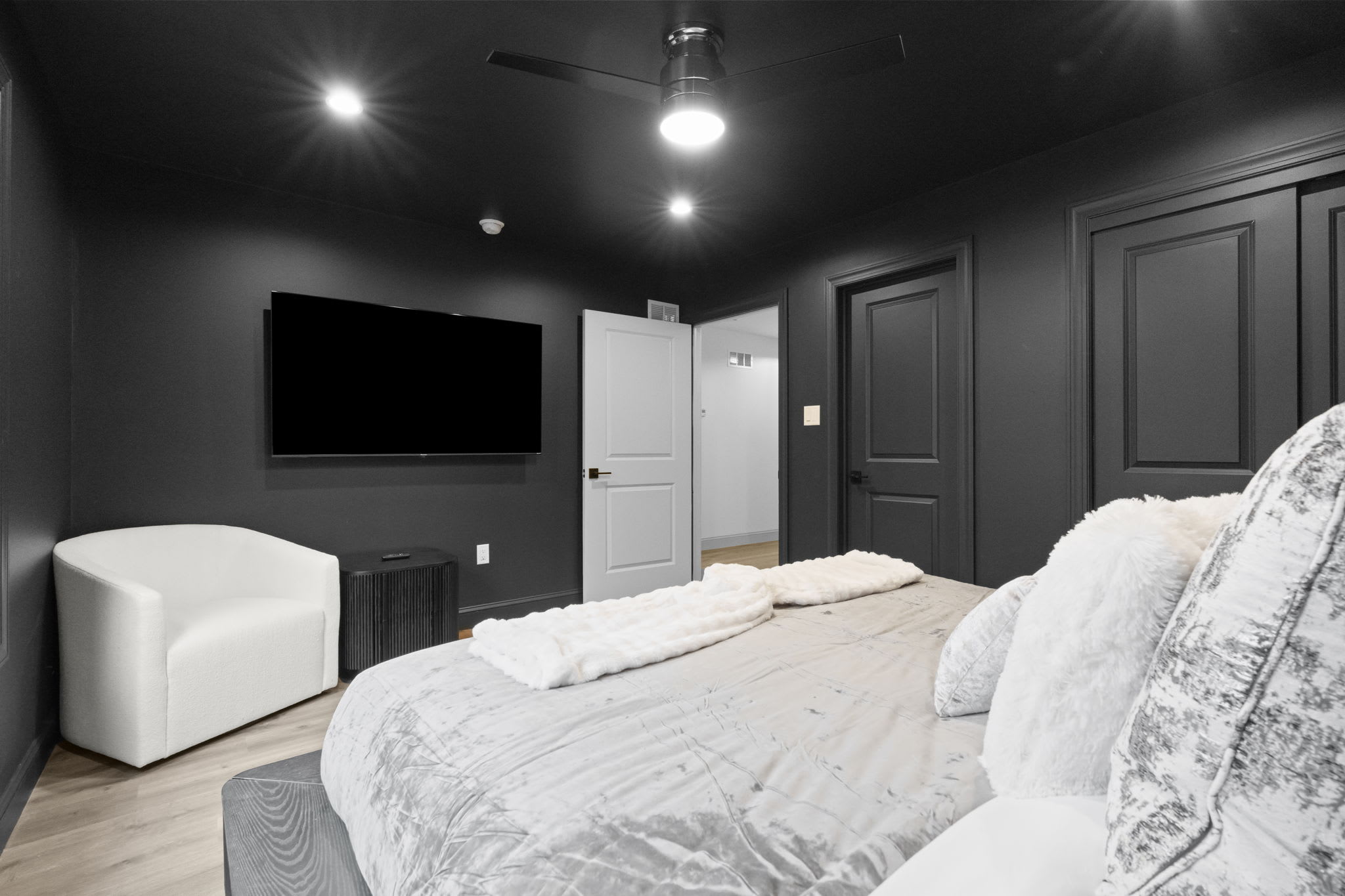 Cozy bedroom with dramatic black accent wall, TV, and comfortable seating area