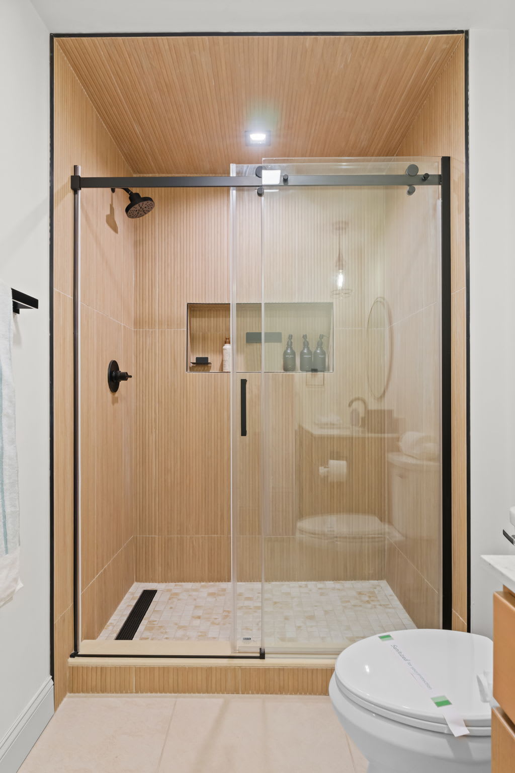 Rinse off in the spacious shower with warm wood paneling and glass enclosure