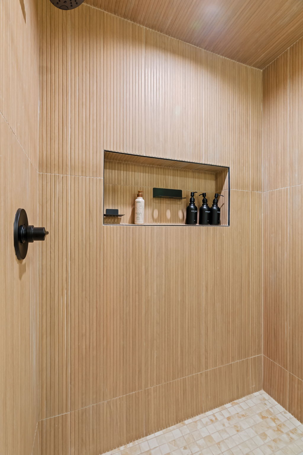 Step into the tile shower with sleek glass door and warm wood surroundings