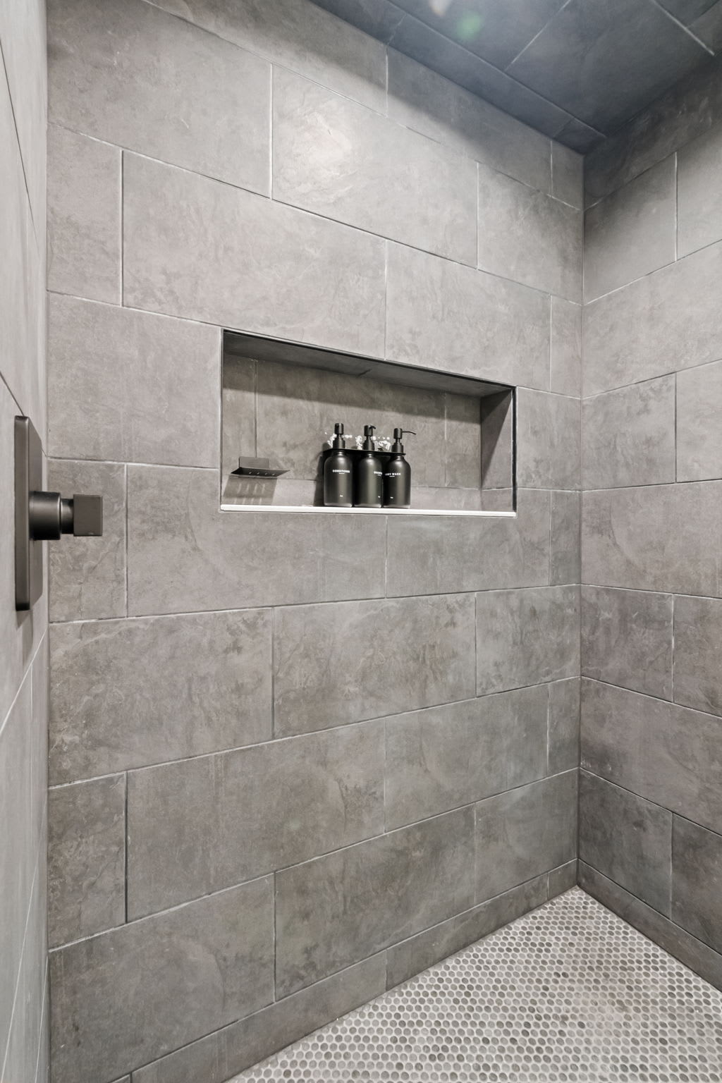 Step into the walk-in shower with modern tile and a built-in niche for essentials