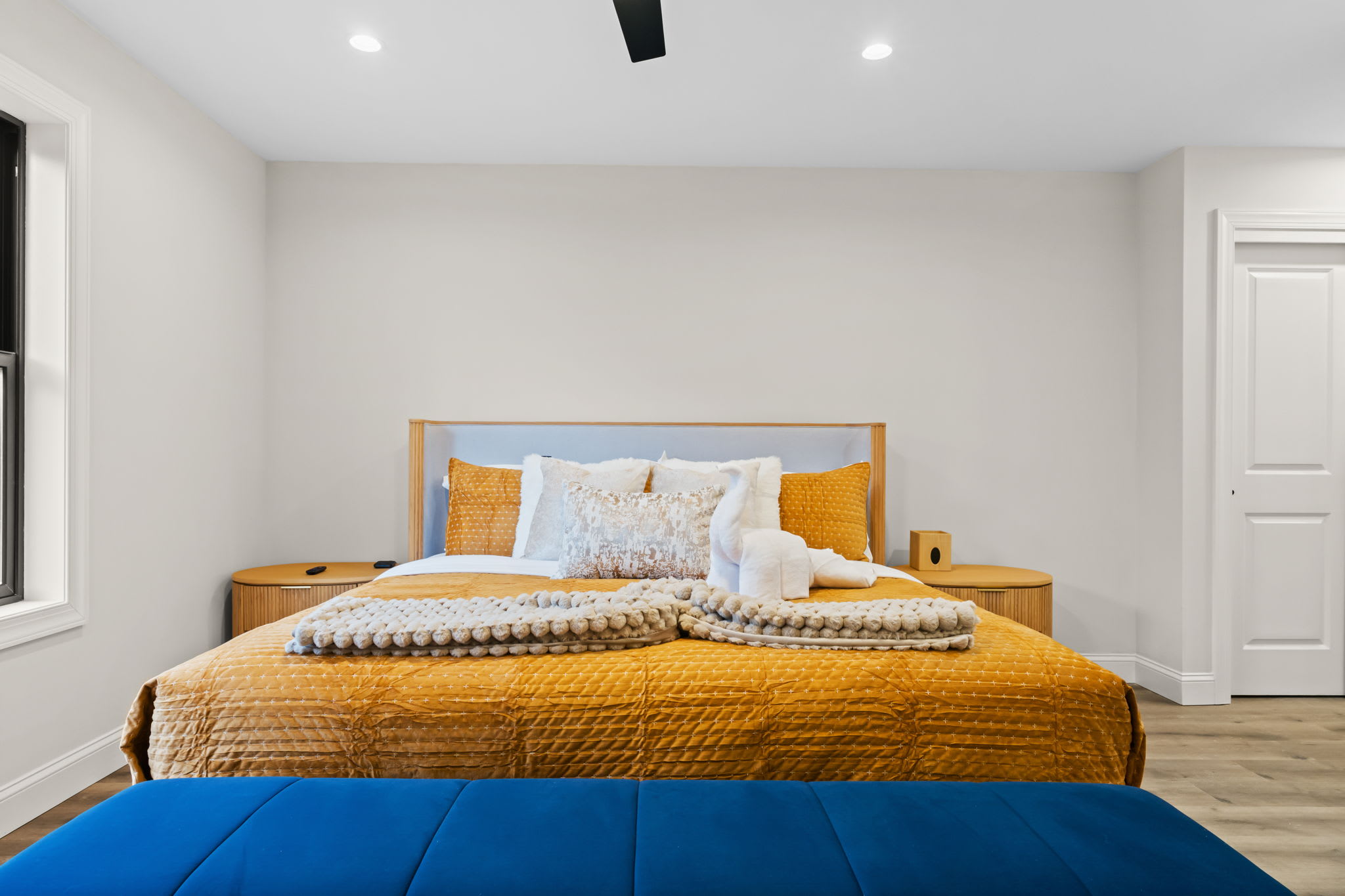 Stylish throw pillows and a velvet bench add charm to this sunny bedroom