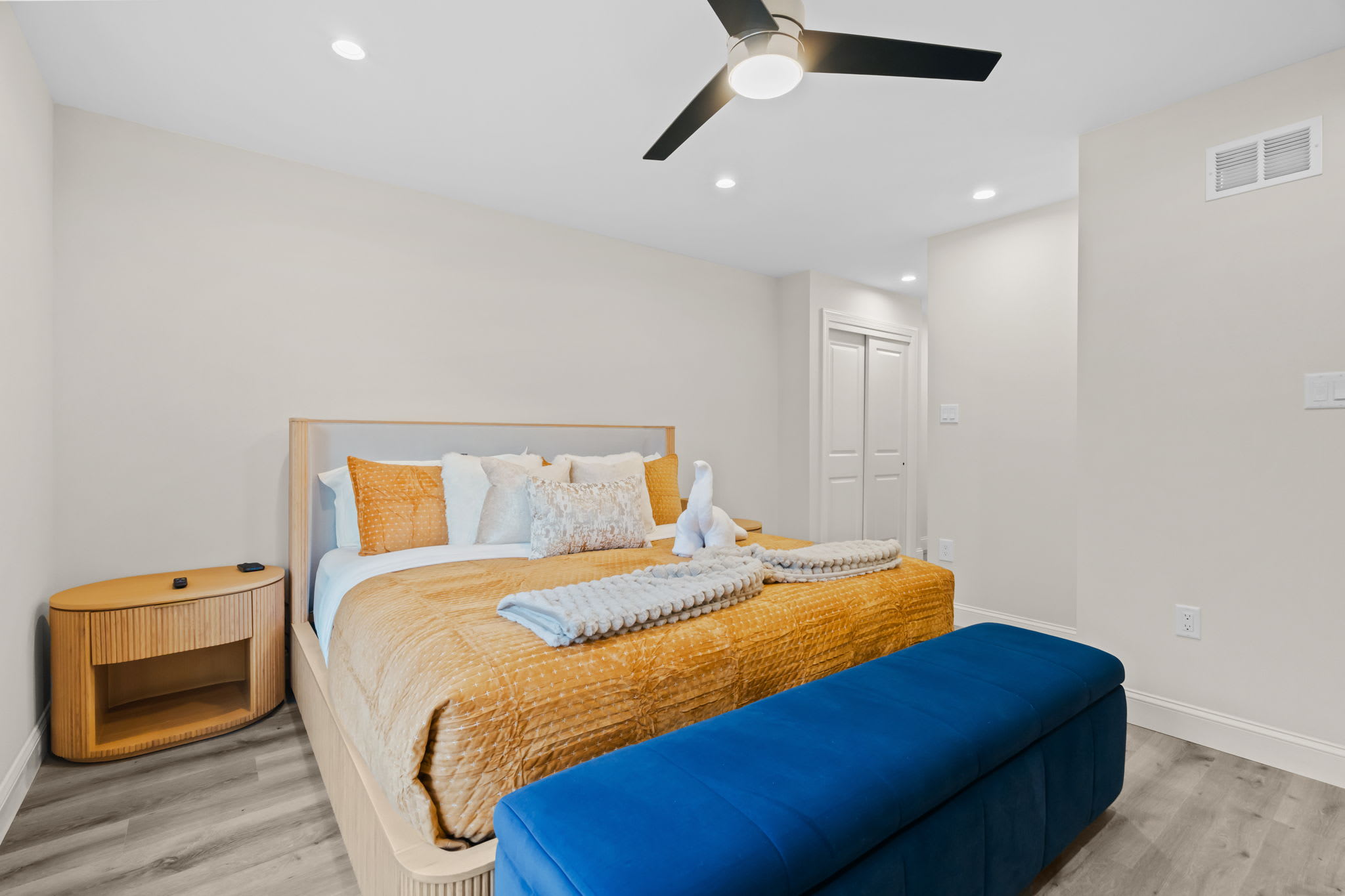 Rest well in this cozy bedroom with warm golden bedding and plush blue bench