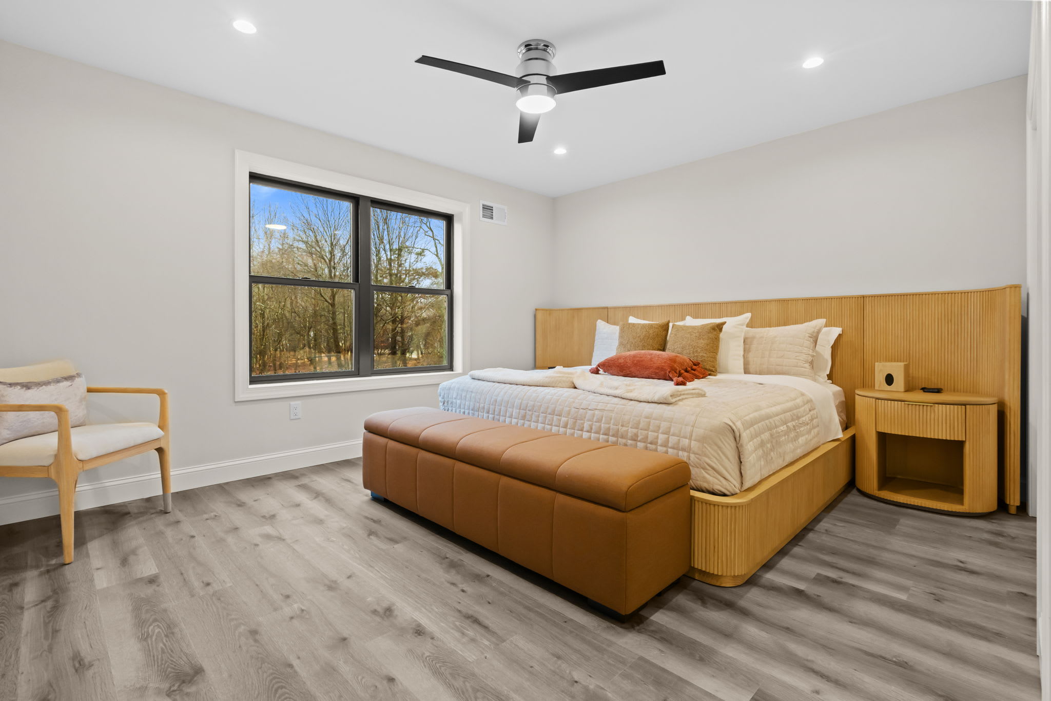 The spacious bedroom features a ceiling fan and wide plank floors for easy living