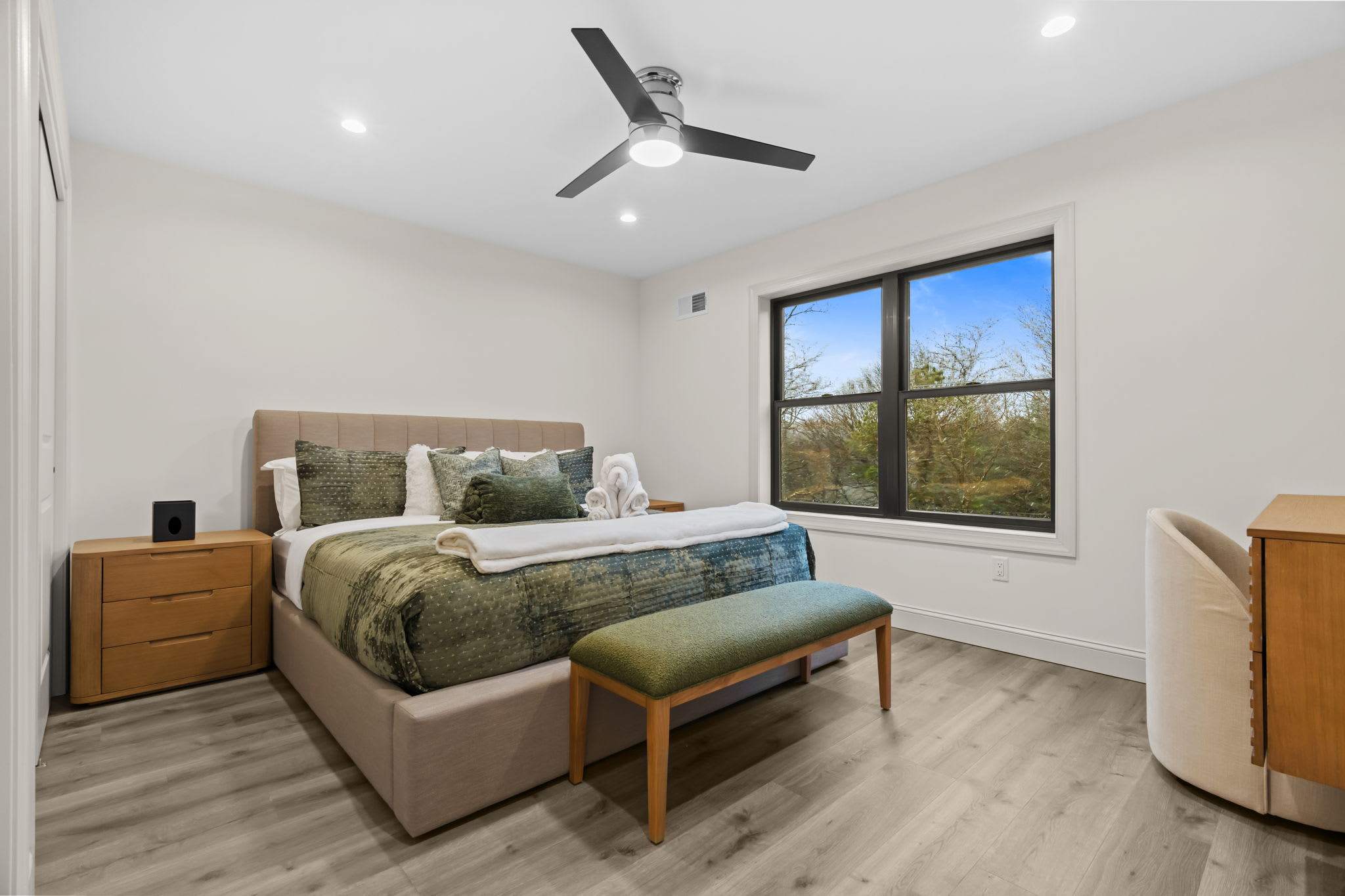 Settle into this restful bedroom with teal accents and serene wooded views