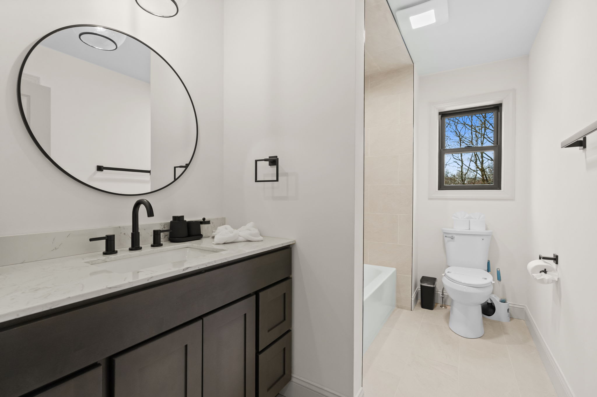 Freshen up at the sleek dark vanity with a stylish round mirror