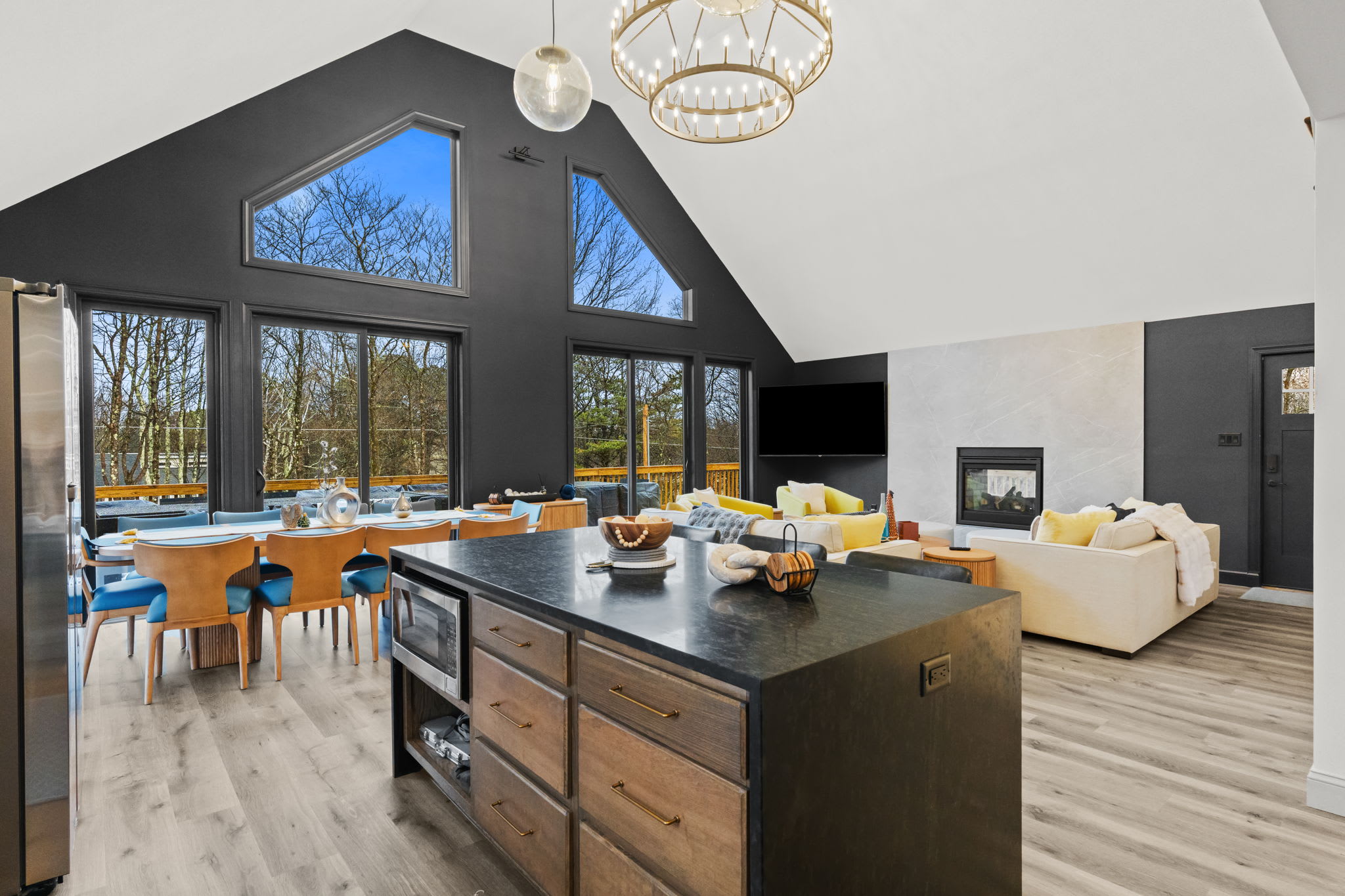 The open floor plan connects the kitchen island, dining area, and living room under soaring ceilings