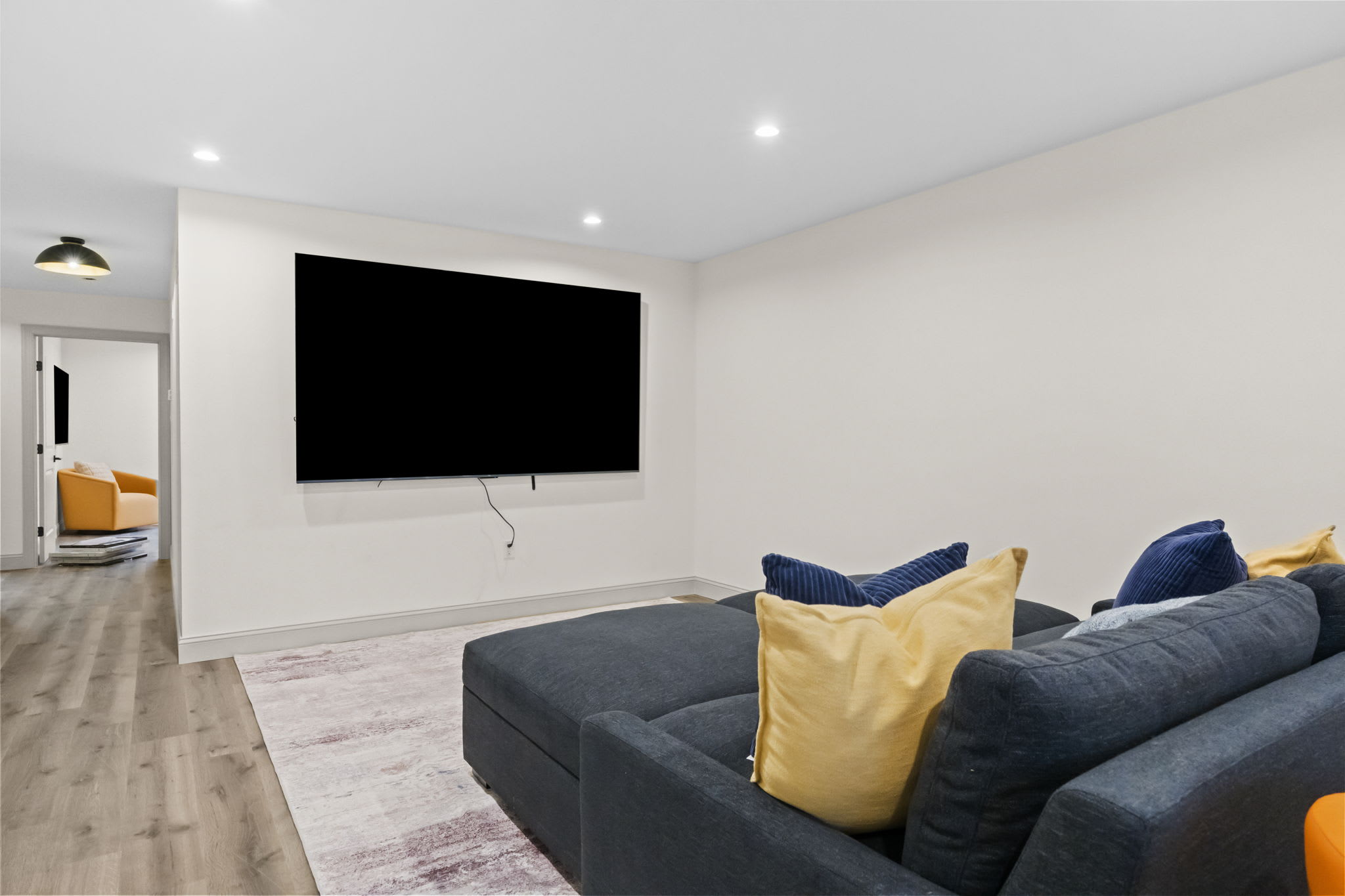 Lower level entertainment room with big screen TV and plush sectional seating