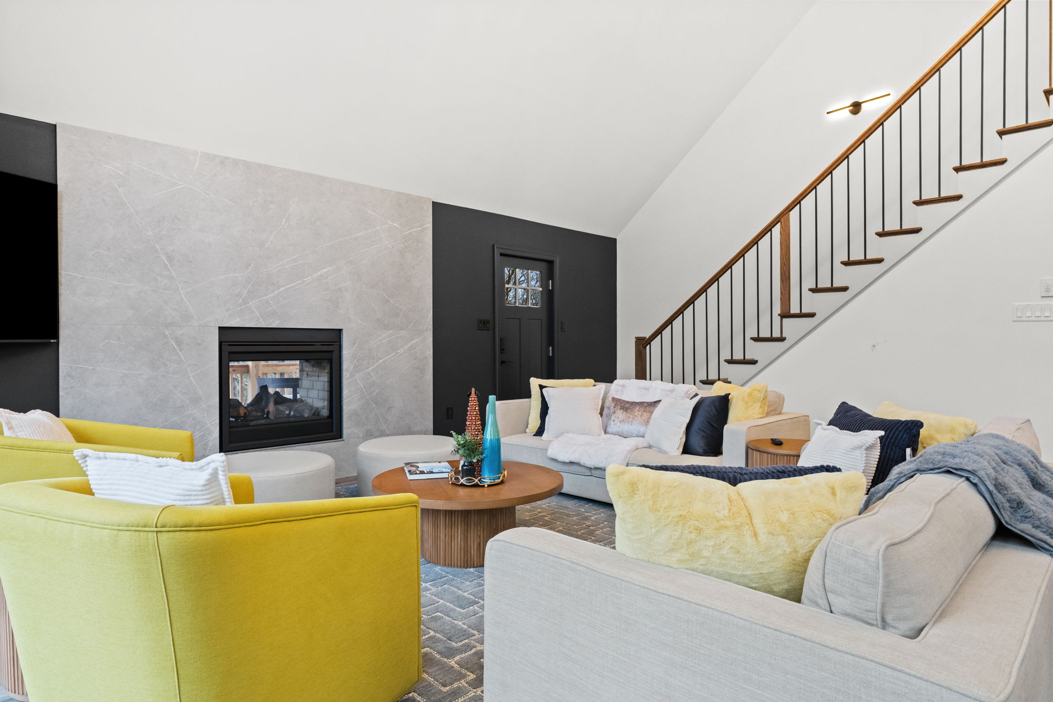 Cozy up by the fireplace in the inviting living room with colorful accents and staircase views