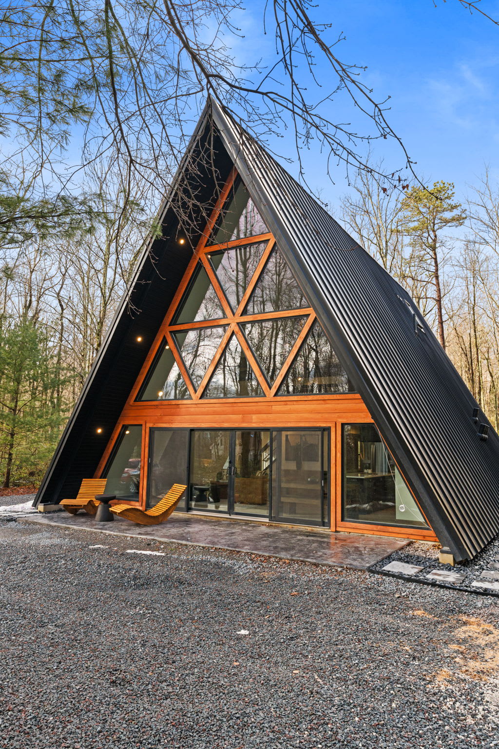 Classic A-frame silhouette nestled among the trees with welcoming front porch