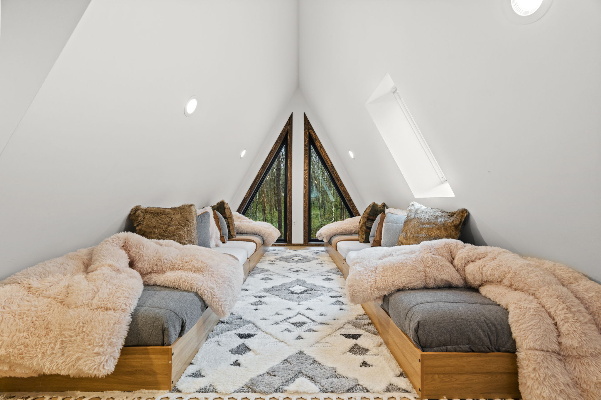 Fourth bedroom loft with two cozy daybeds and geometric A-frame windows