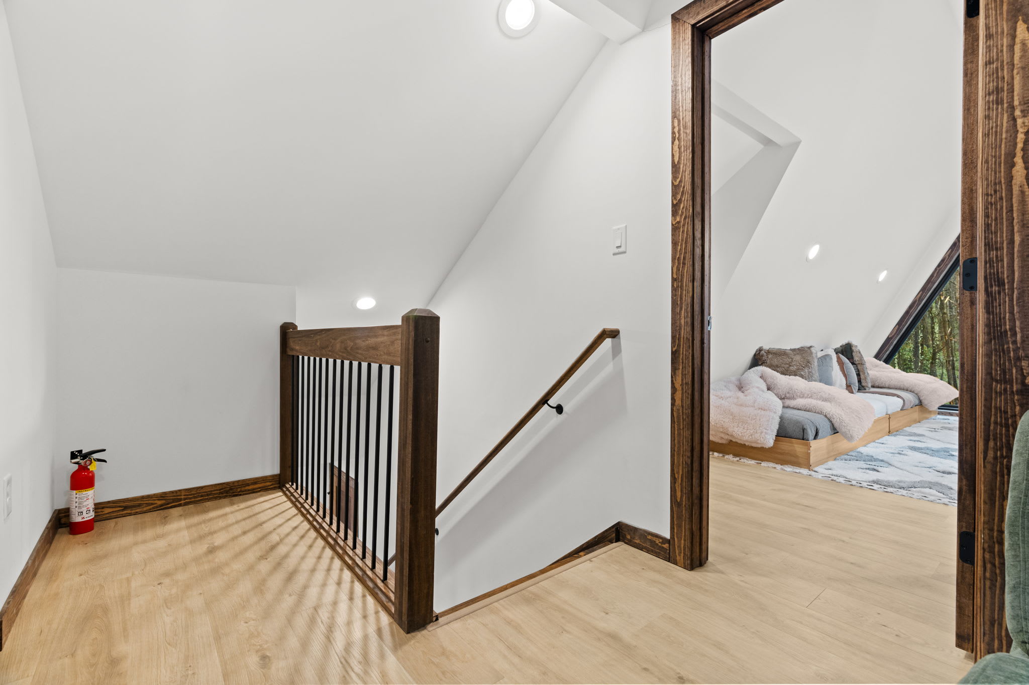 Wooden staircase leads up to the loft with a cozy egg chair reading nook