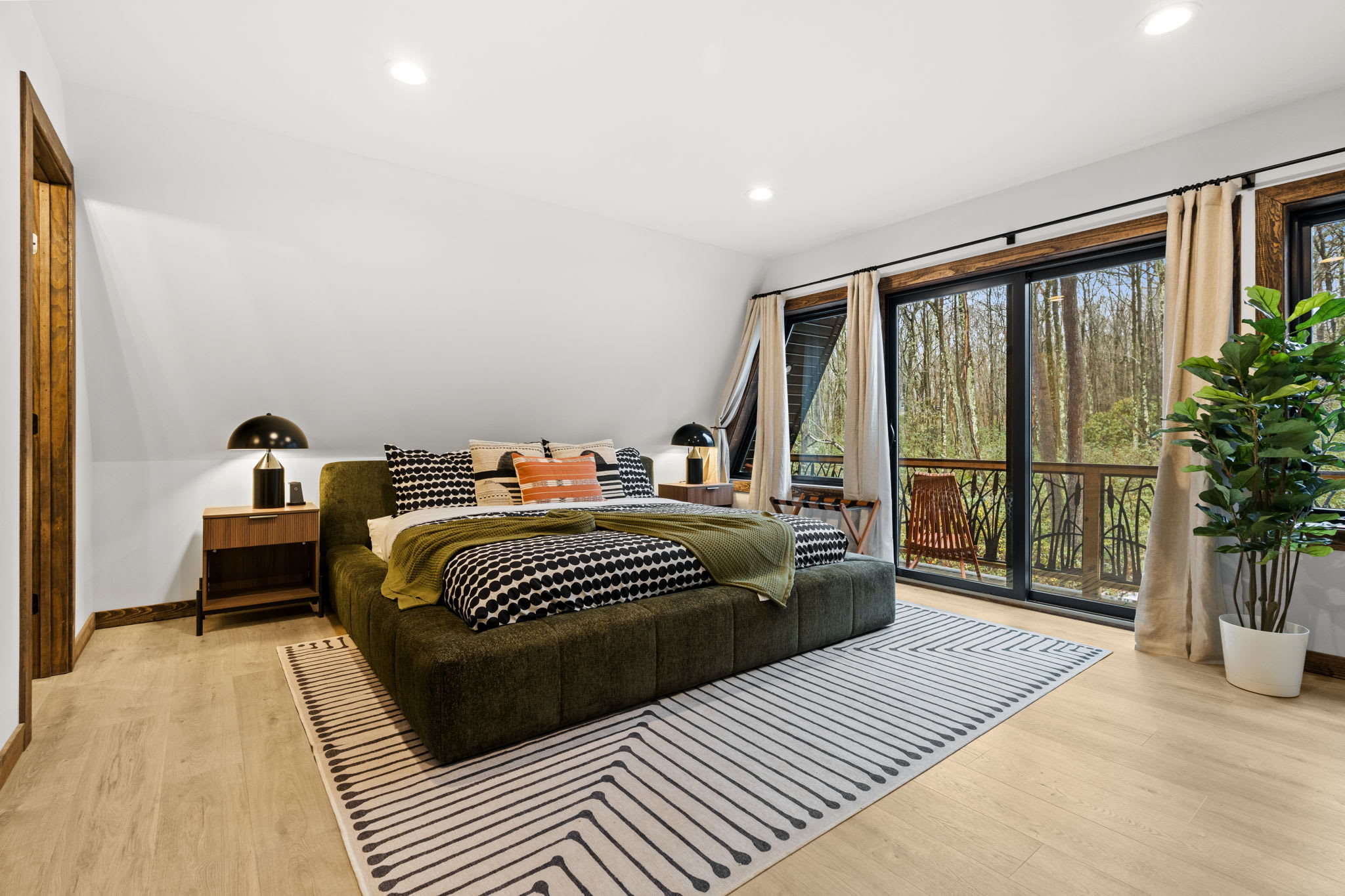 Third bedroom retreat with plush green velvet bed and forest views through large windows