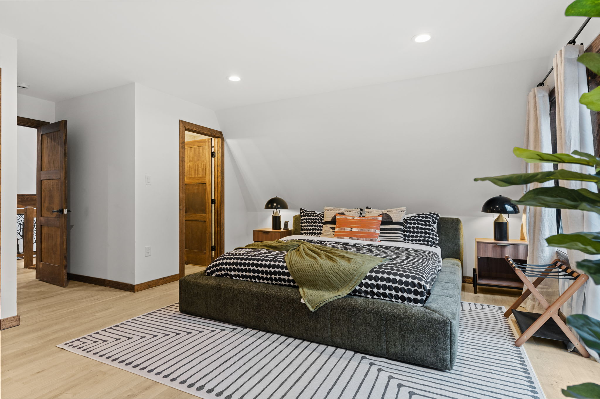 Bright third bedroom with lush houseplants and an ensuite bathroom nearby