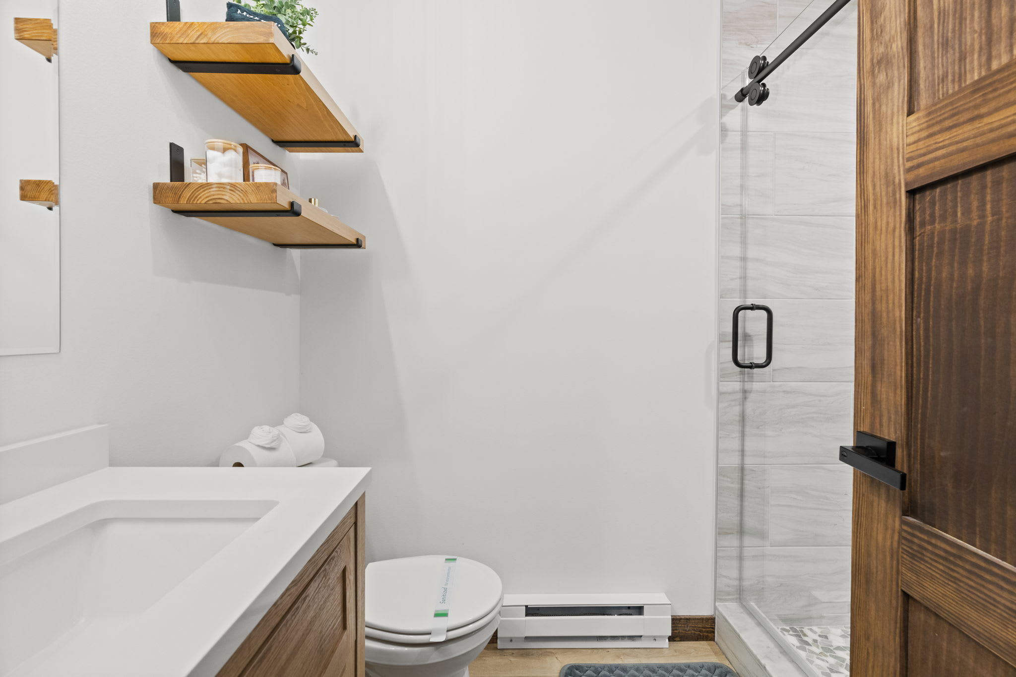 Modern ensuite bathroom with walk-in shower, wooden accents and fresh greenery