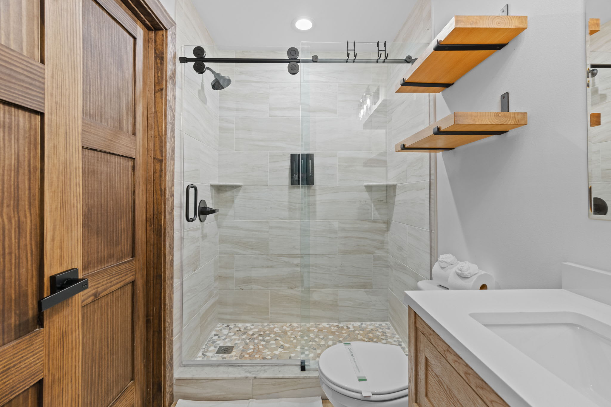 Primary bathroom with walk-in marble shower and wooden floating shelves