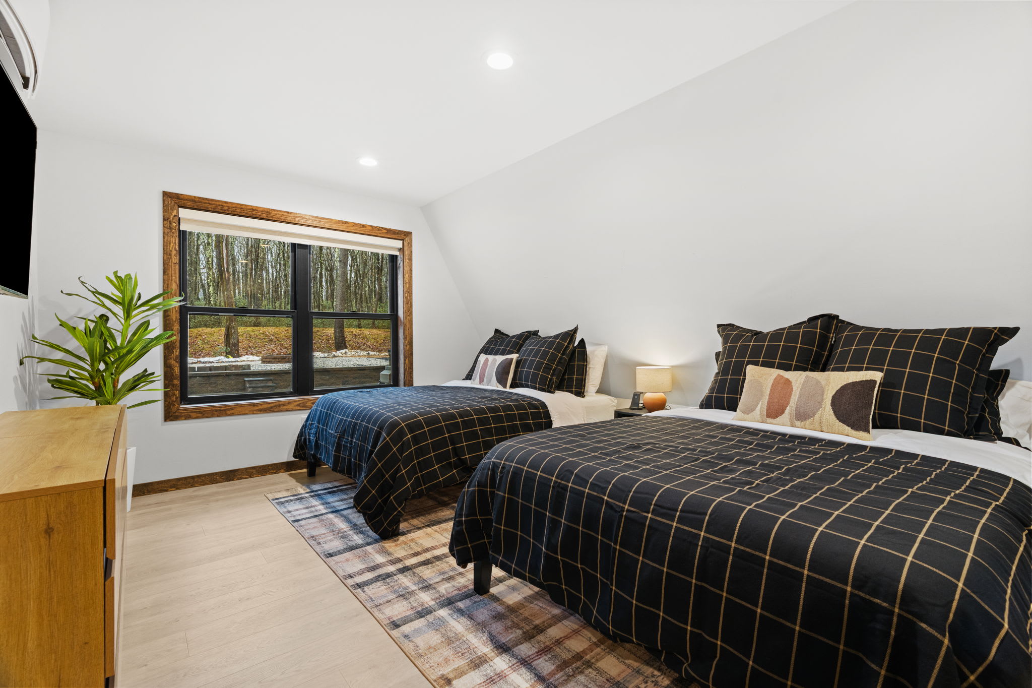 First bedroom retreat with two cozy beds and forest views through large windows