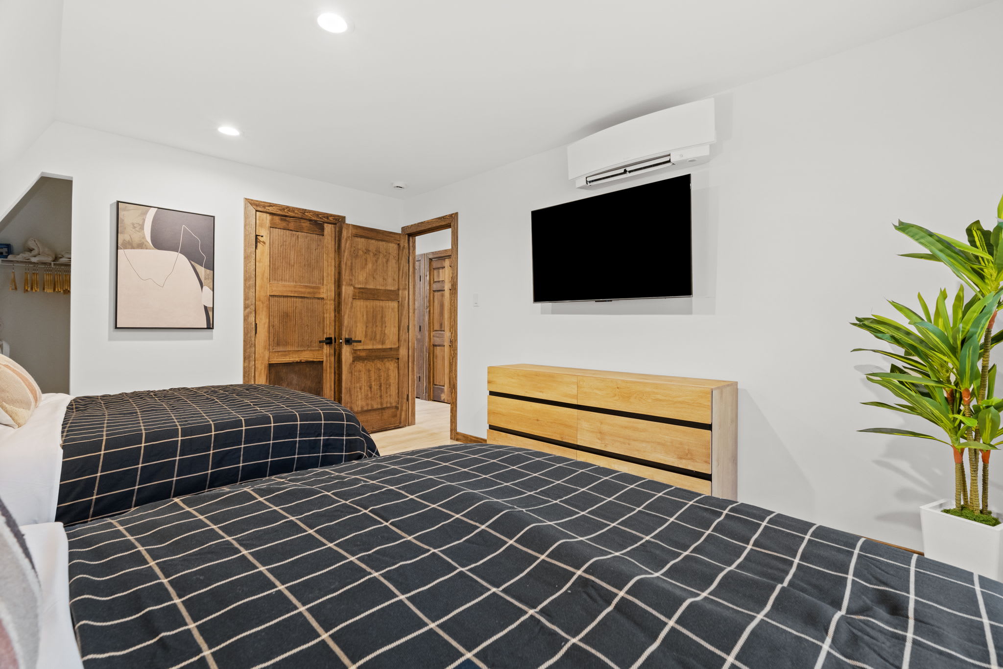 Spacious first bedroom with closet space and a wall-mounted TV for relaxing evenings