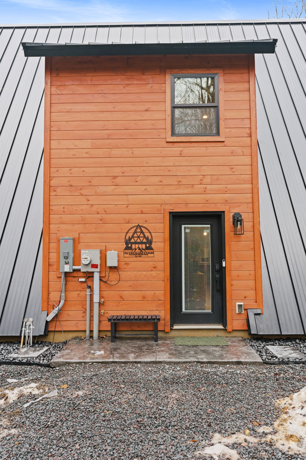 Side entrance with warm orange door and modern metal siding welcomes your arrival