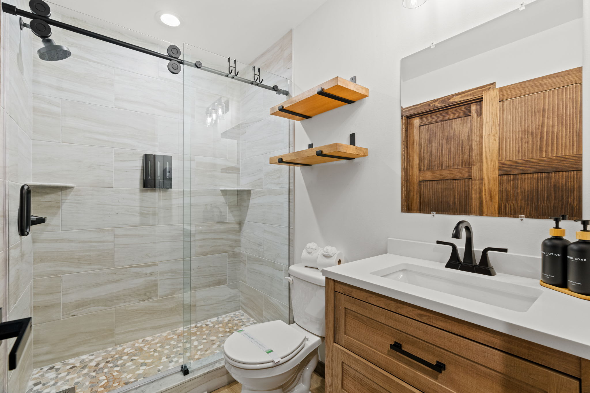 Spacious primary bathroom with wood vanity and glass-enclosed shower