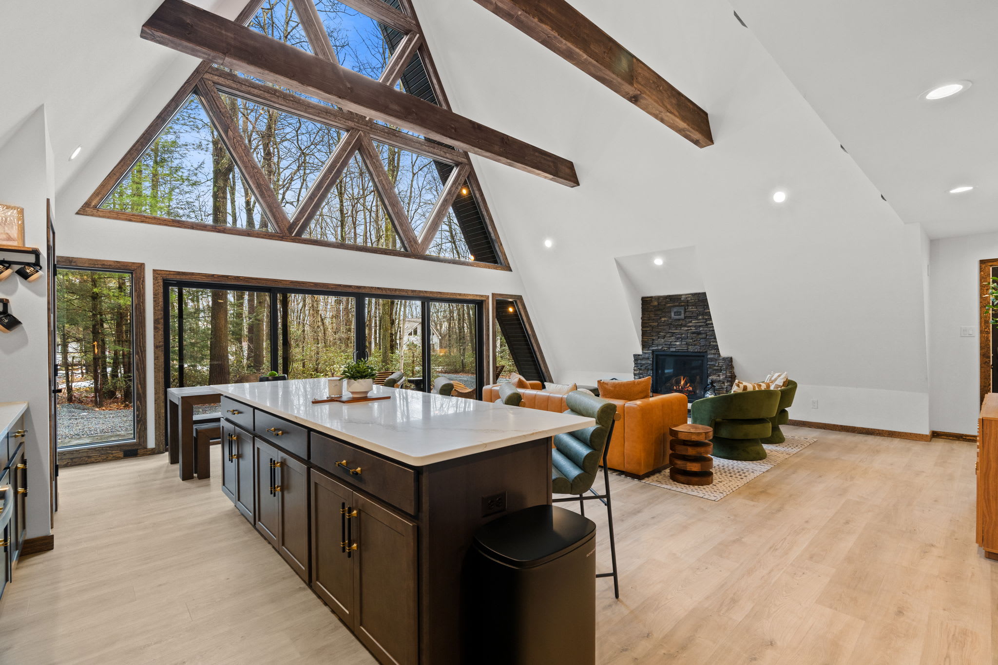Modern kitchen island with bar seating and forest views through dramatic windows