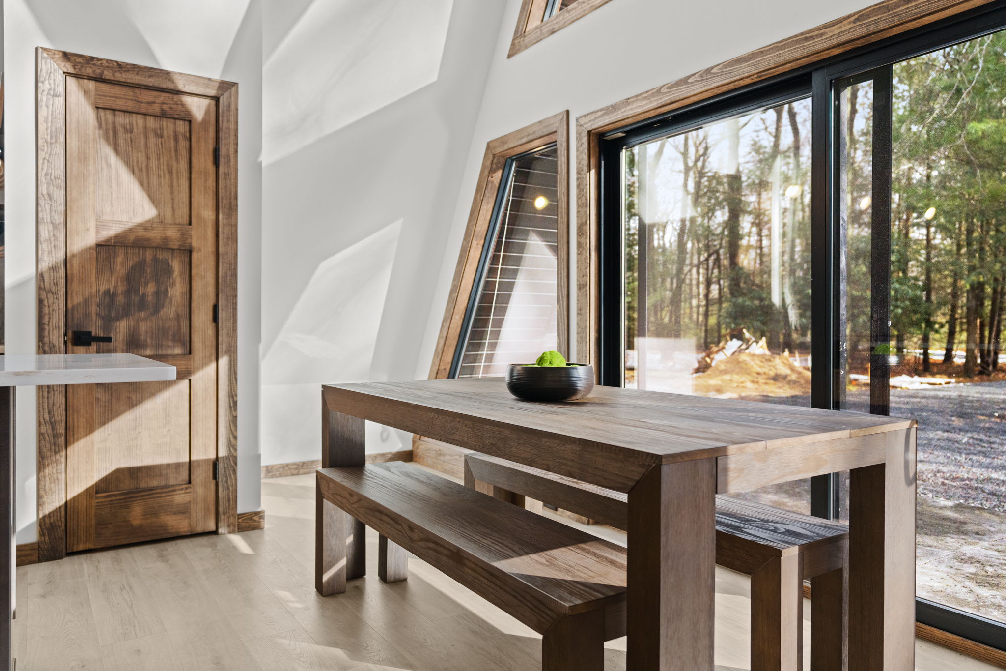 Dramatic wood beams frame the A-frame windows with treetop views beyond